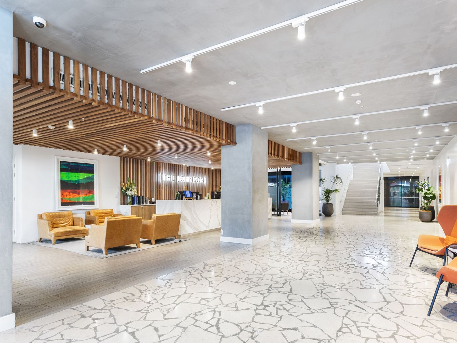 Modern lobby interior with wood accents, track lighting and minimalist furniture.