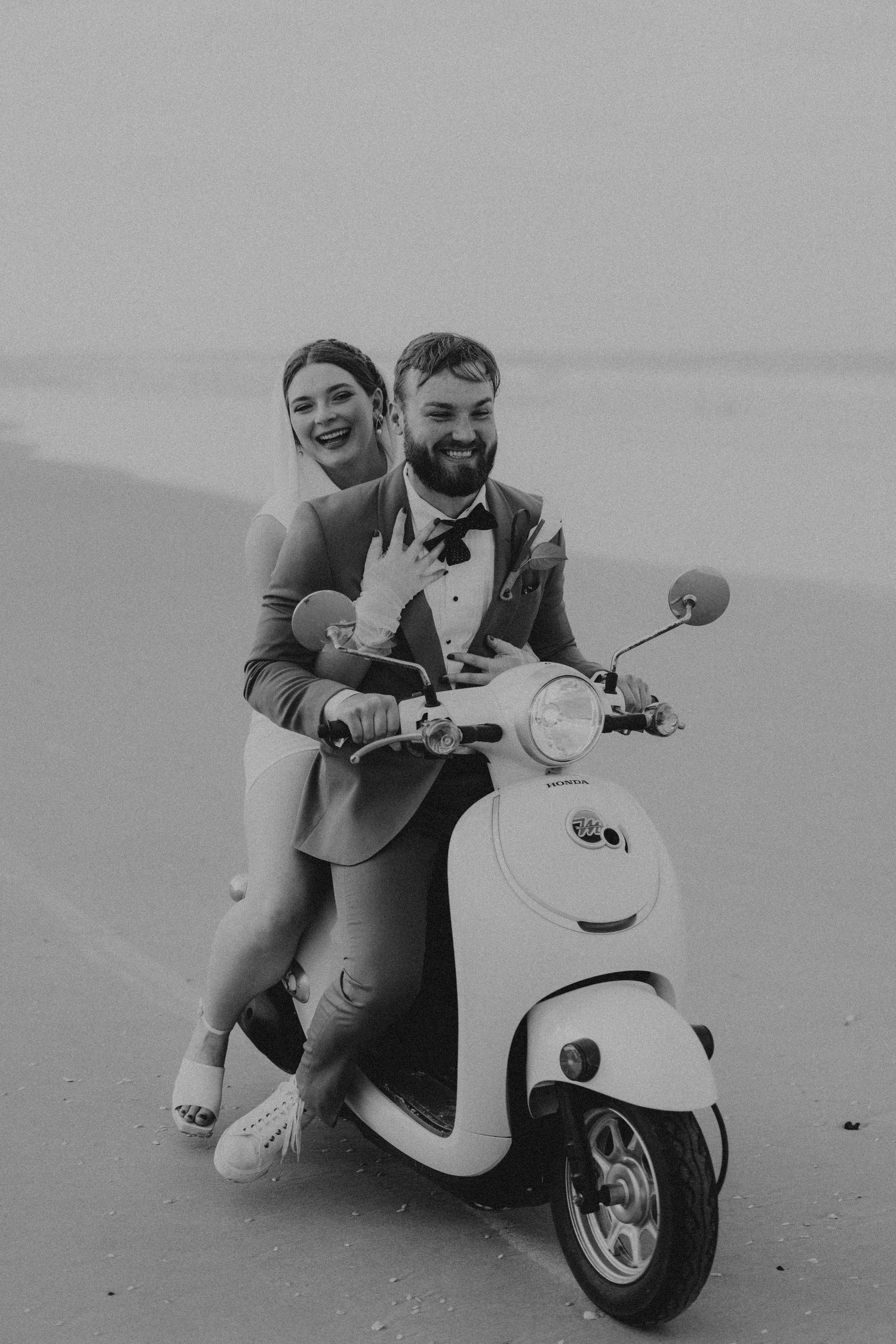 Black and white photo series showing a scooter laid down on beach while someone takes creative perspective photos.