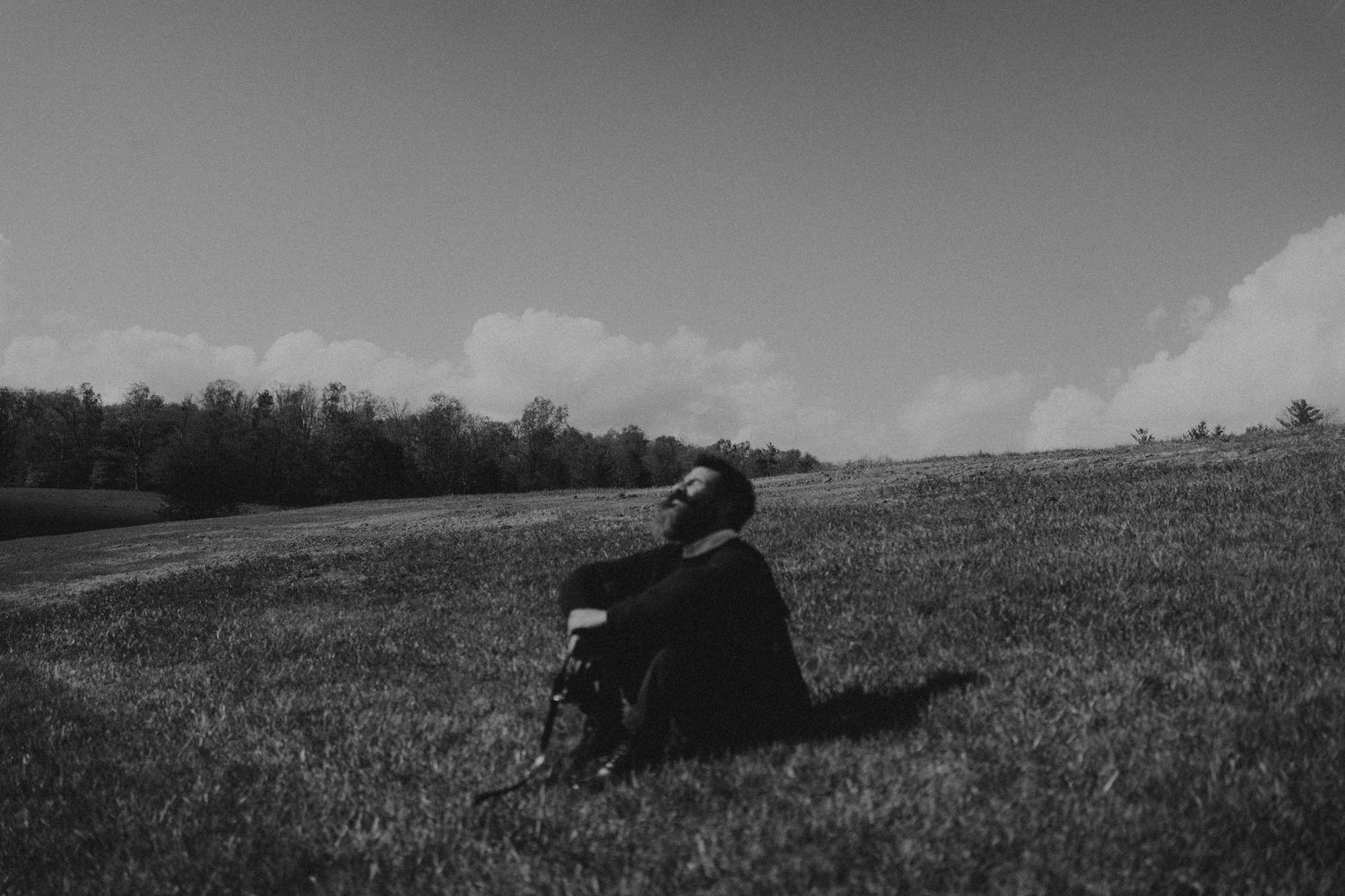 Silhouetted figure lies in a peaceful grass field against a moody black and white sky.