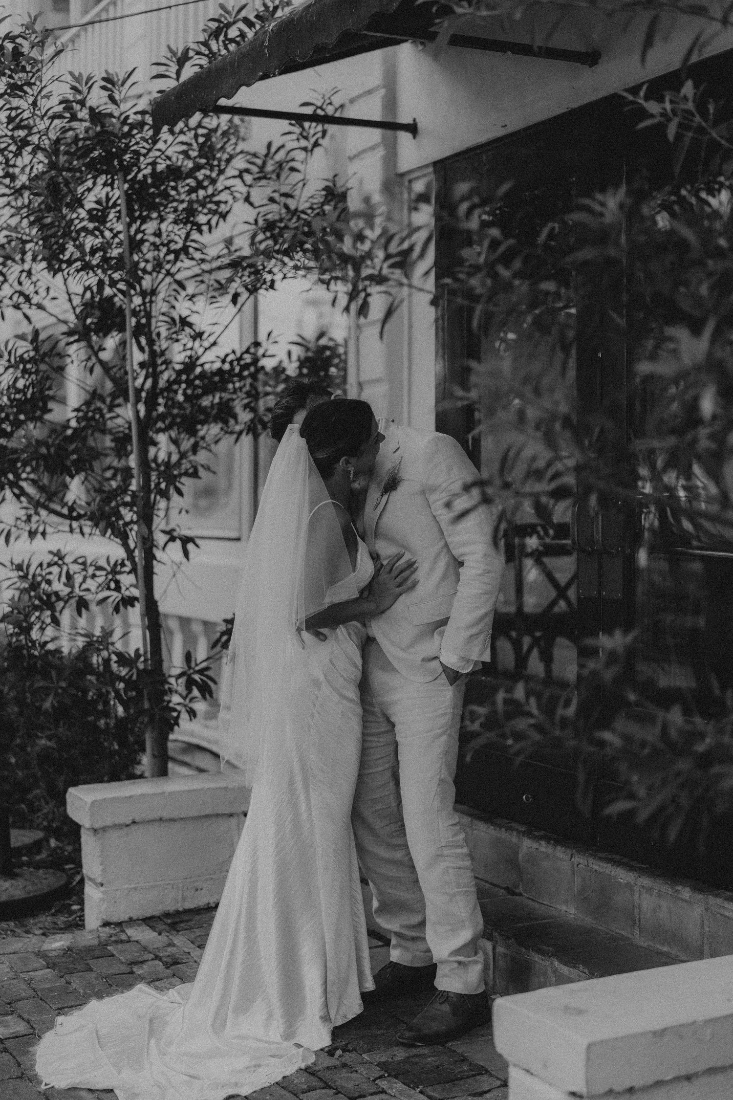 Five vintage black and white photos show two figures in domestic scenes with trees and architecture visible behind them.