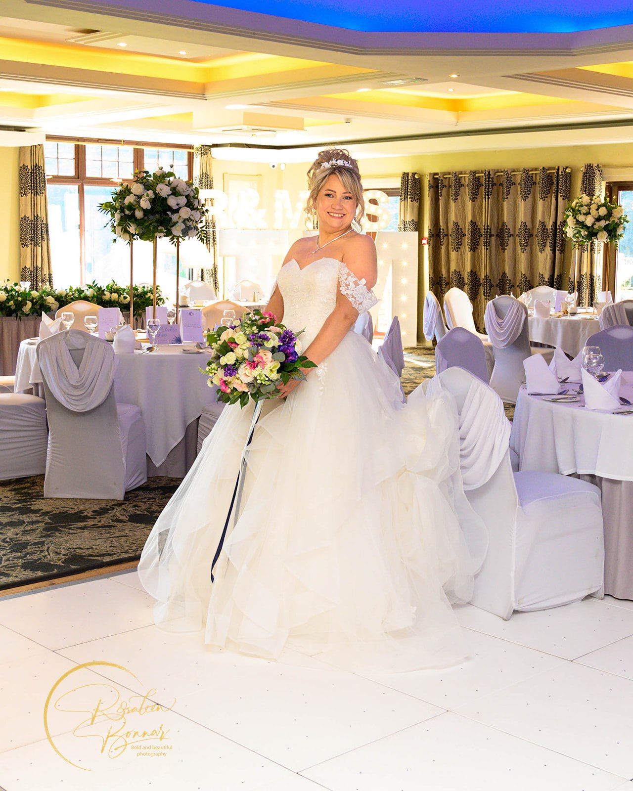 An elegant wedding reception venue decorated in white and gray with chair covers and ambient blue lighting. Dalziel Park, Motherwell.