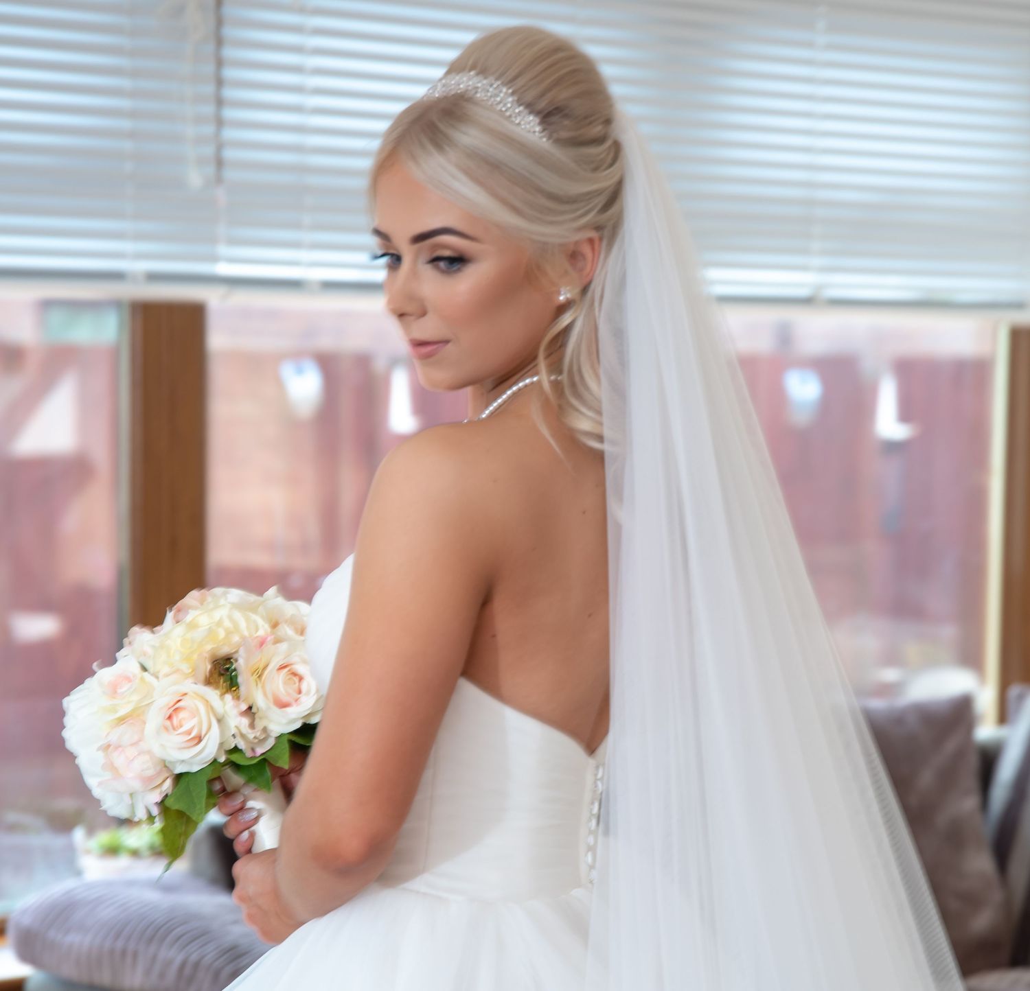 Bride in a strapless white wedding dress holding a pastel bouquet bathed in beautiful natural light.