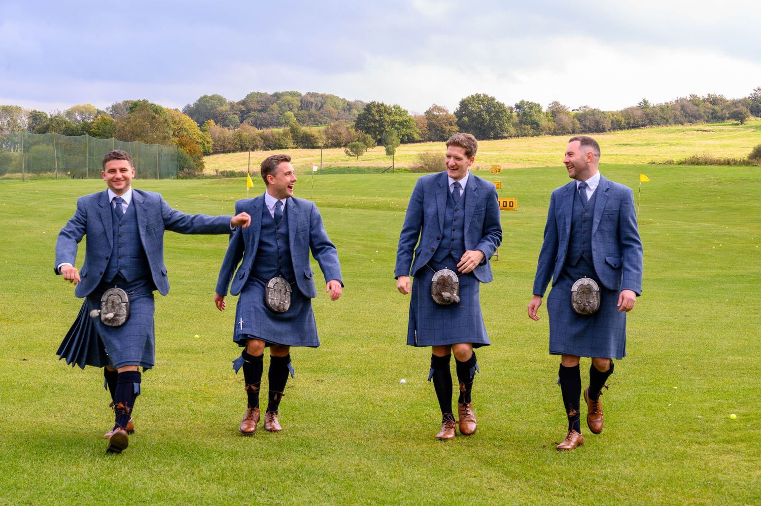 Four men in matching blue kilts walking across green Scottish countryside.Roodlea Barn, Ayrshire