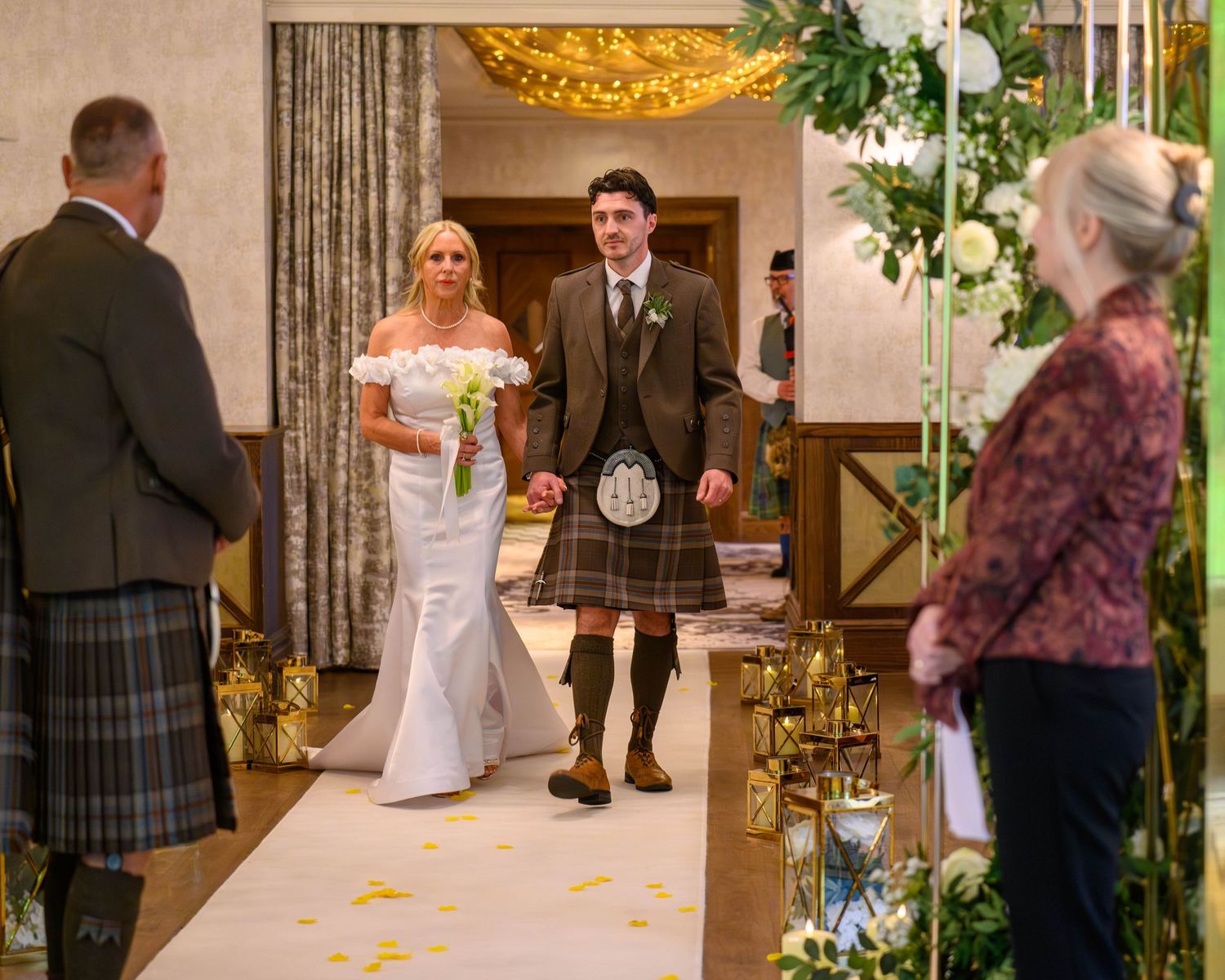 Bride and groom walk down the aisle in a Scottish wedding venue, groom wearing a traditional kilt.