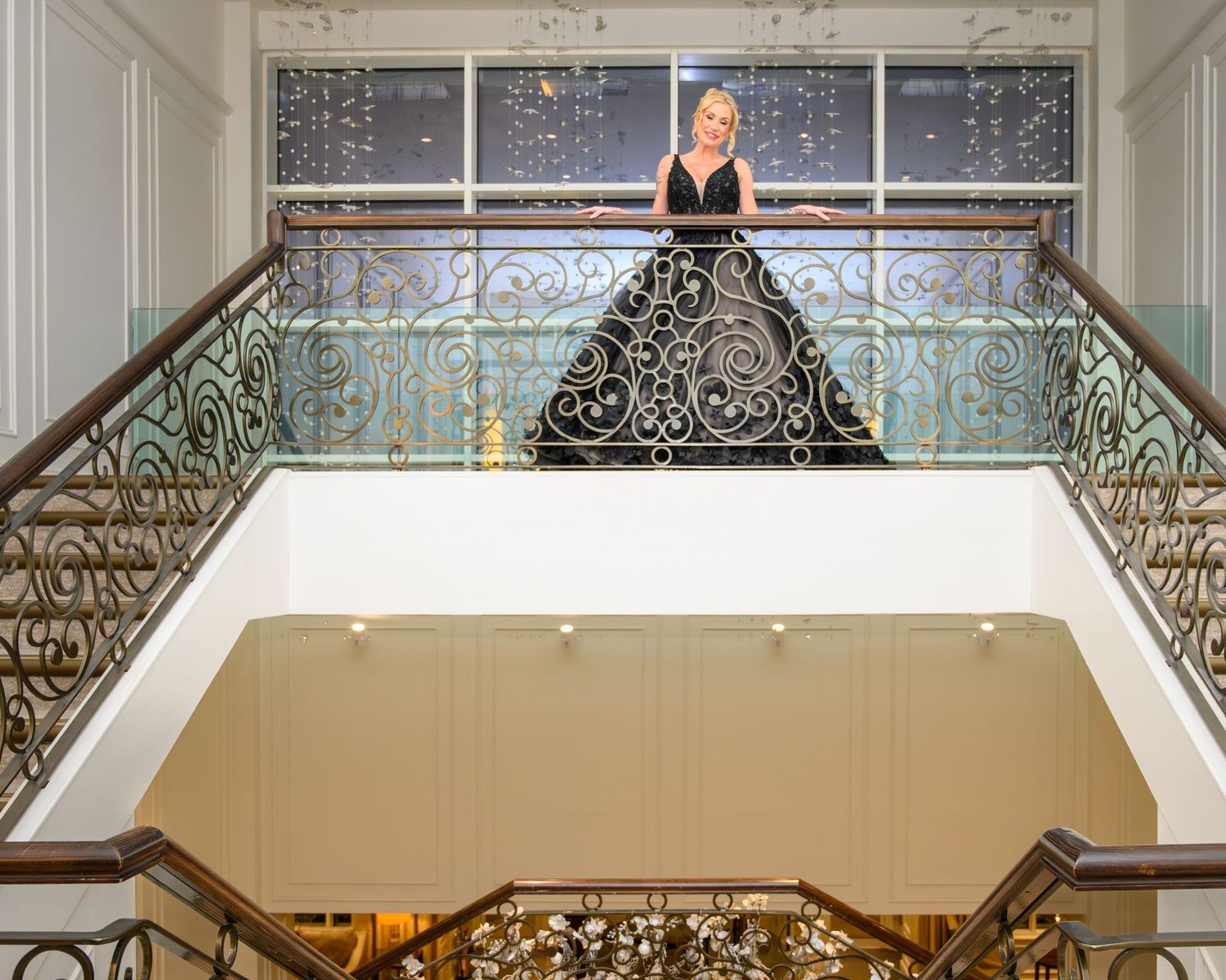 Elegant white staircase with ornate iron railings and chandeliers in a grand interior space.Seamill Hydro.