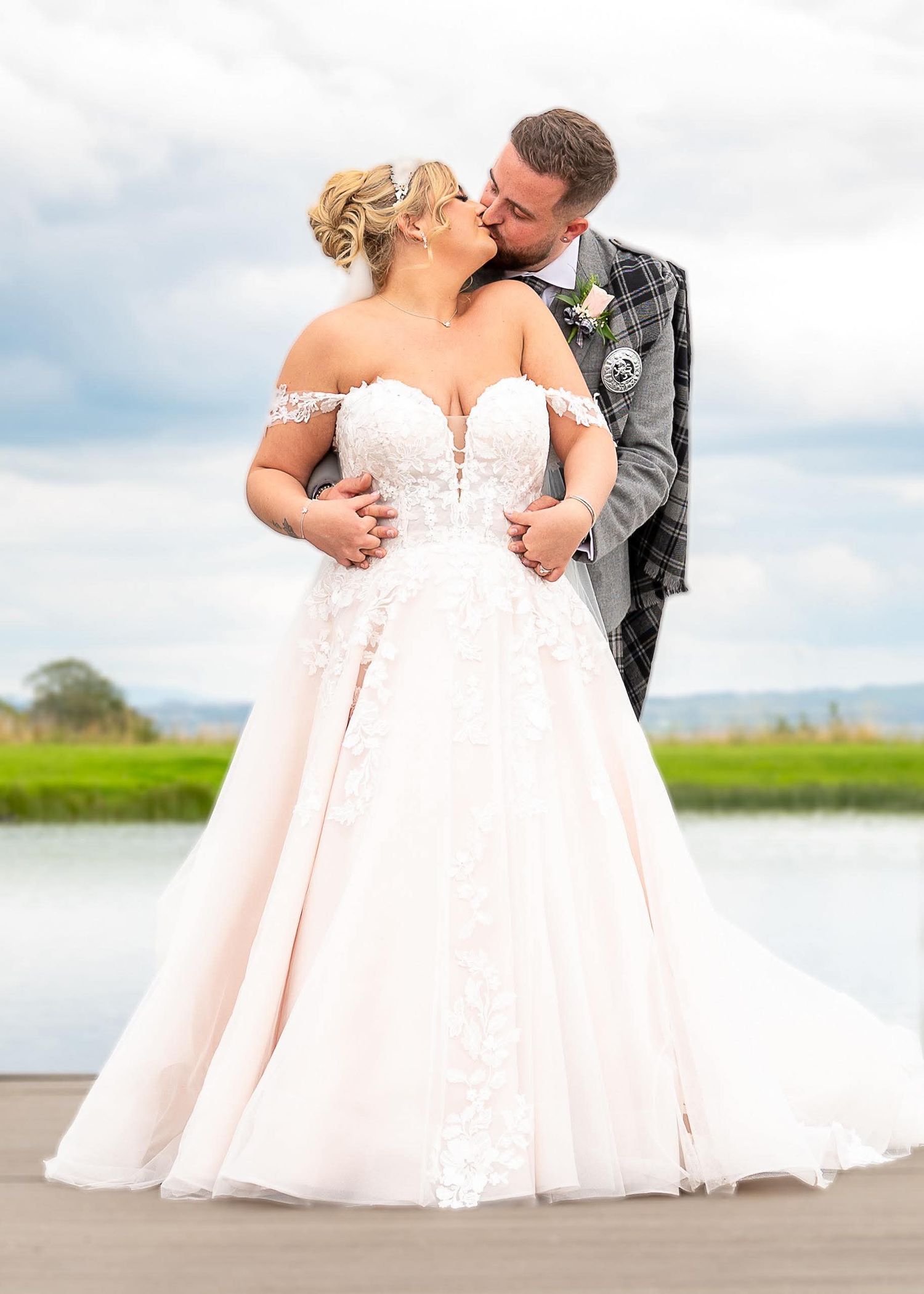 A couple in wedding attire shares intimate moments by a waterfront in a series of romantic photographs at The Vu in Bathgate.