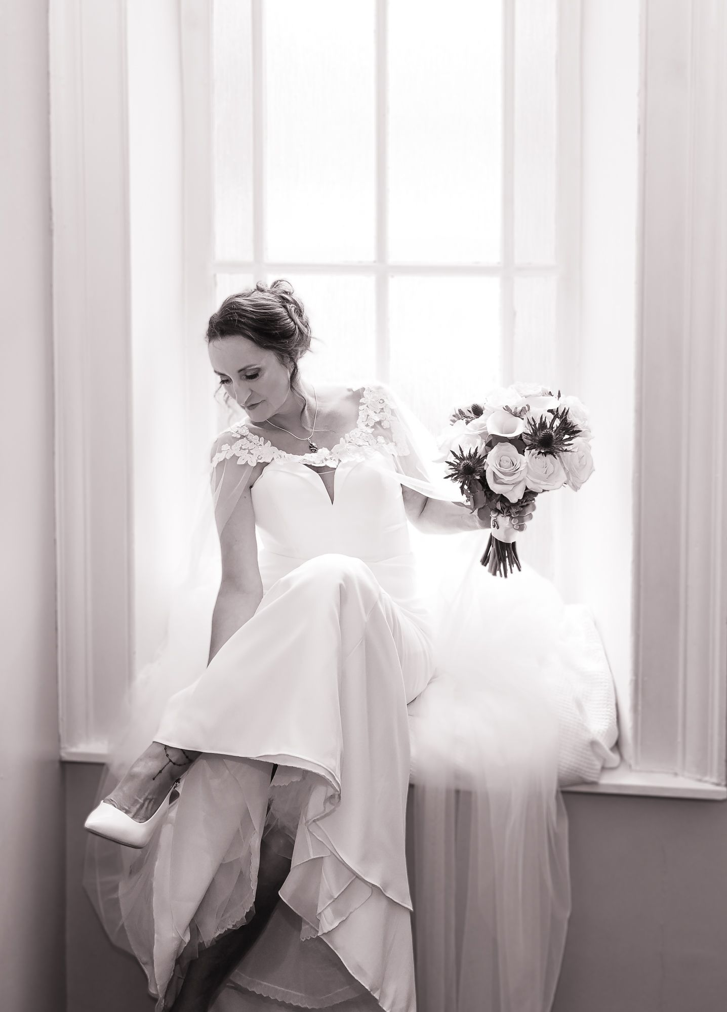 Classic black and white bridal portrait by window with bouquet and elegant white dress. Dalgety Bay