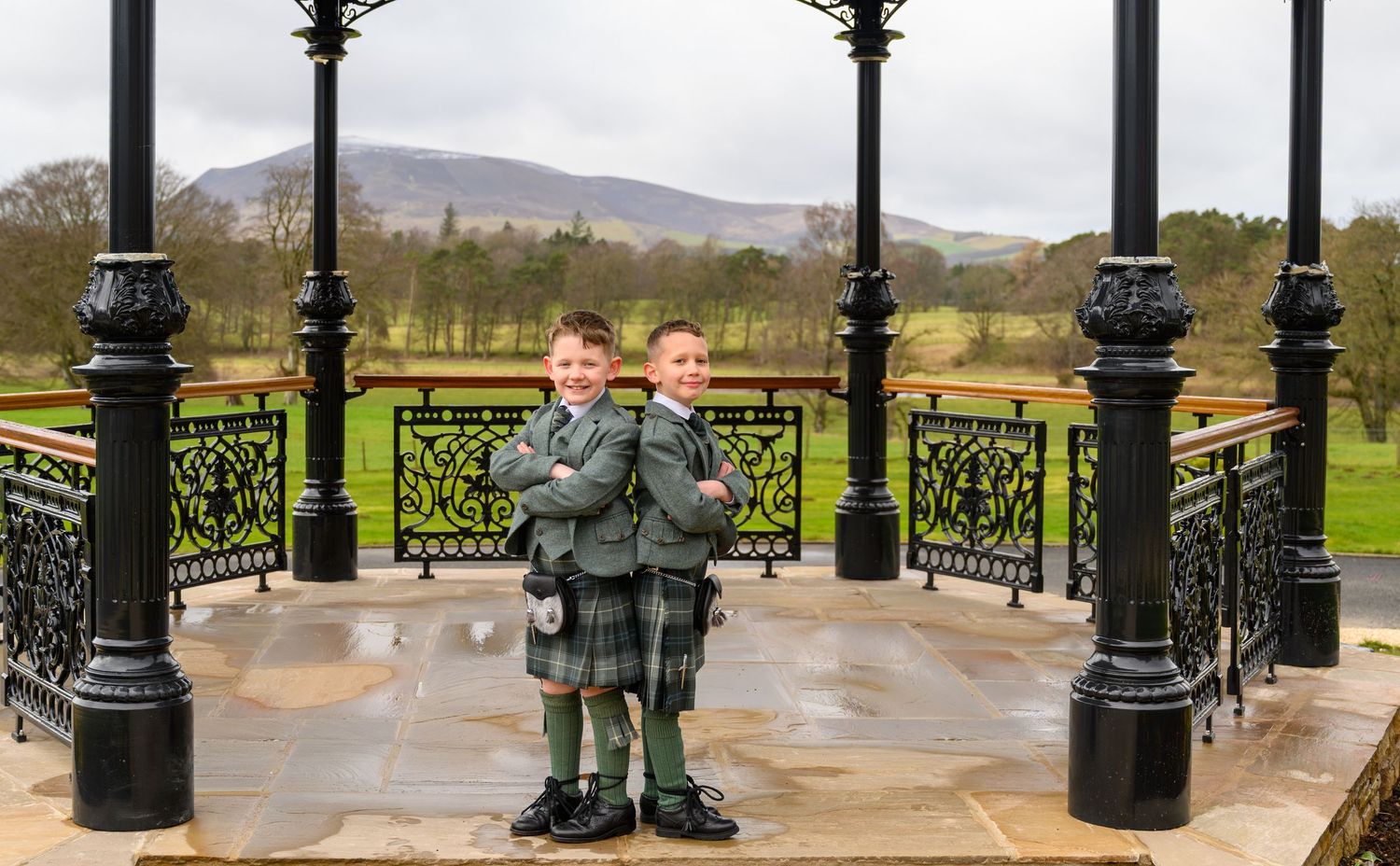 Ornate black metal lamp posts line a curved balcony overlooking mountains and countryside in the distance.
