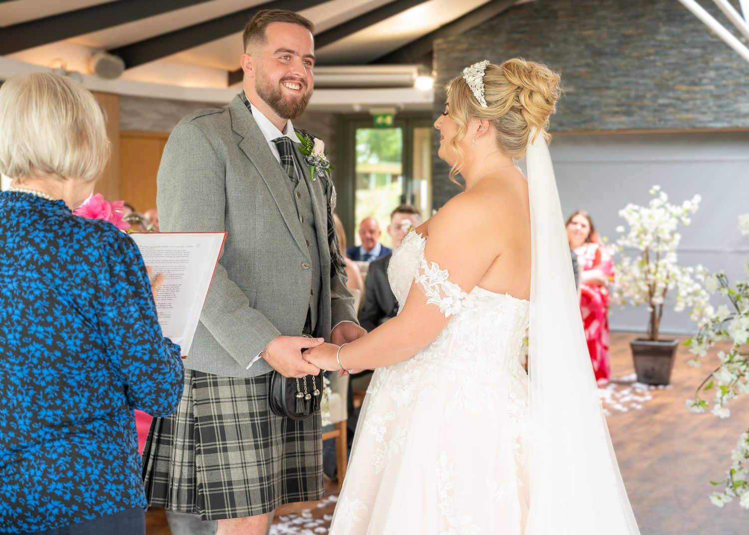 A couple shares a joyful moment during a Scottish-themed wedding ceremony with the groom wearing a traditional kilt. The VU, Bathgate