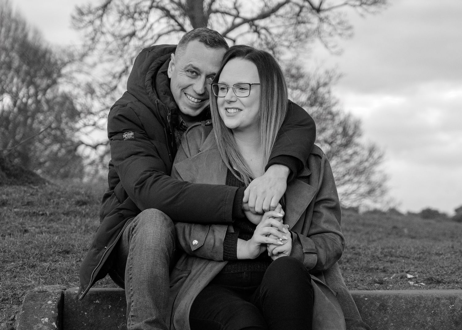 A black and white portrait of a couple embracing on wooden steps at Bothwell Castle