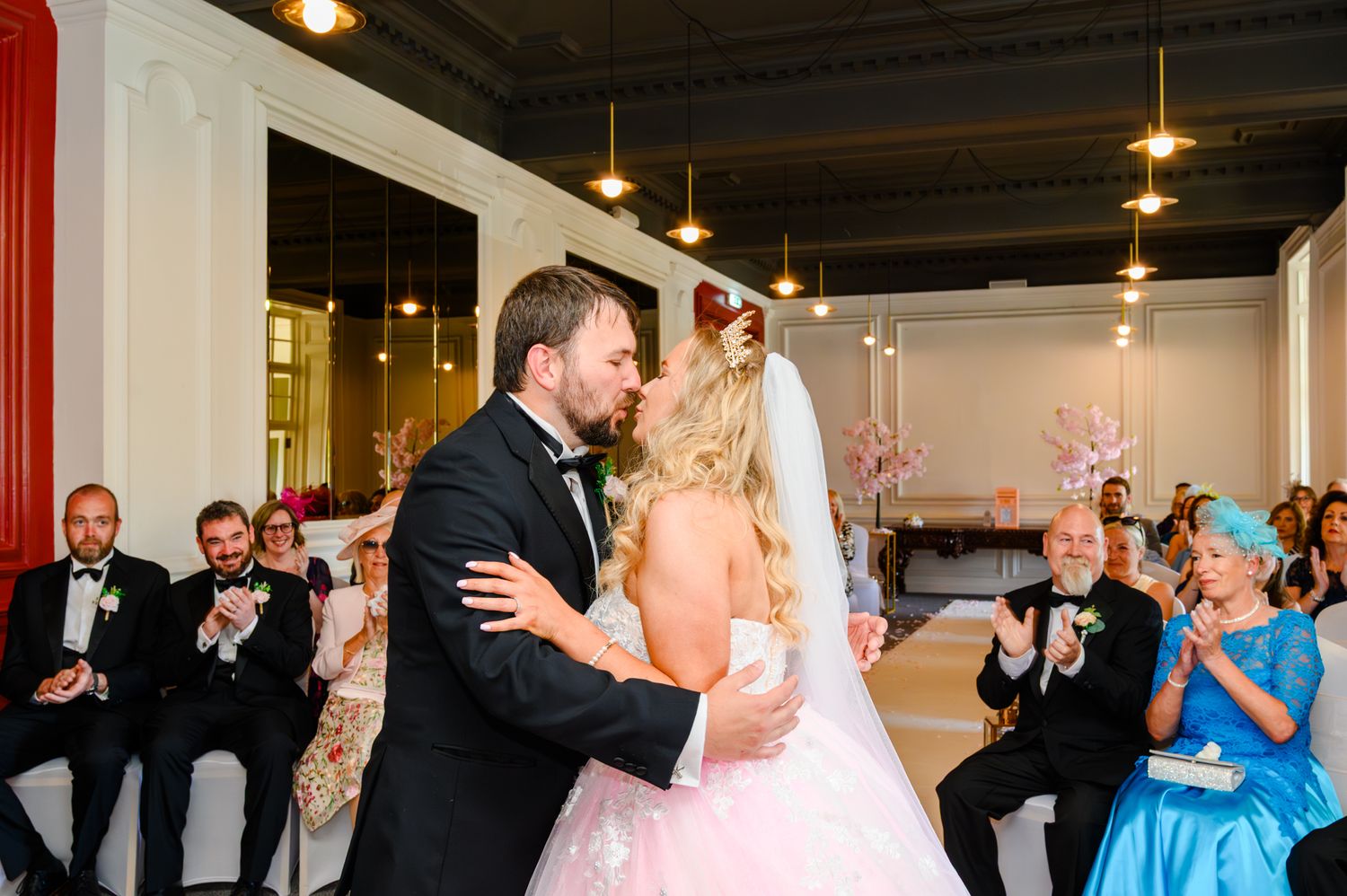 Wedding guests celebrate with the bride and groom during a joyous indoor reception at Peebles Hydro.