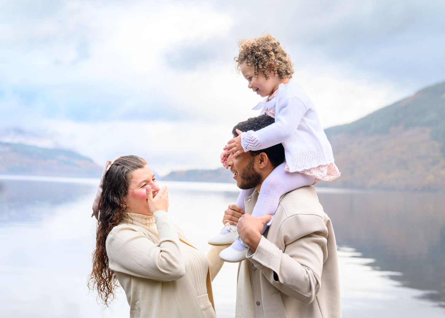 A couple shares an intimate moment during their wedding photoshoot by a scenic mountain lake. Loch Lomond.