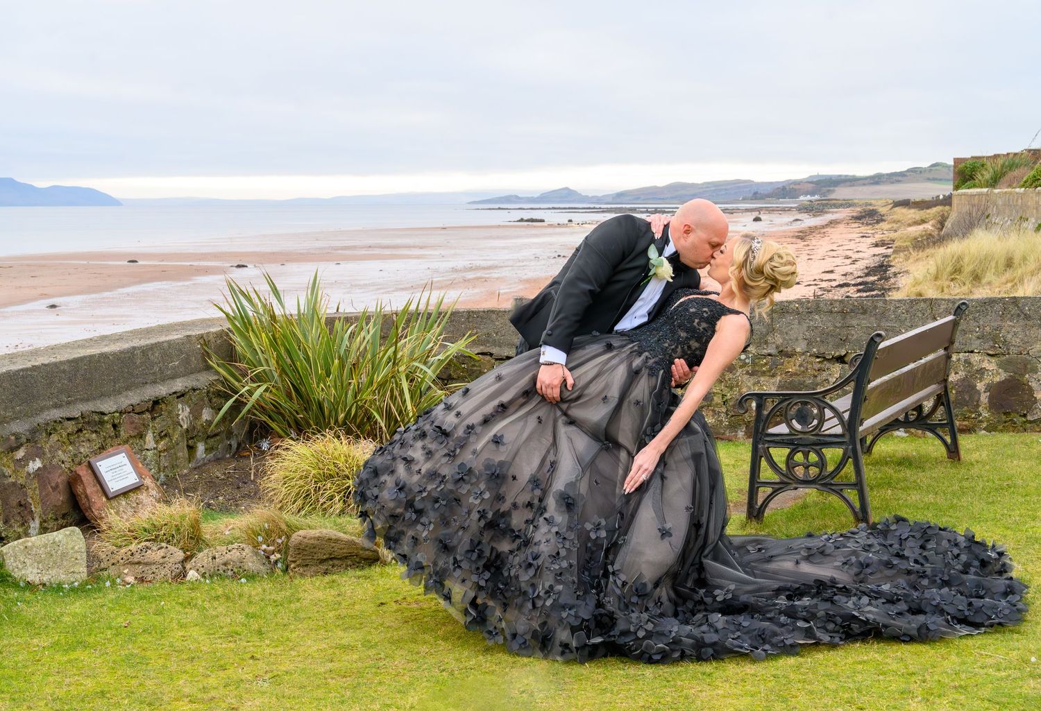 A person performs a series of plank exercises on a wooden bench overlooking a scenic coastal landscape. Seamill Hydro in Ayshire