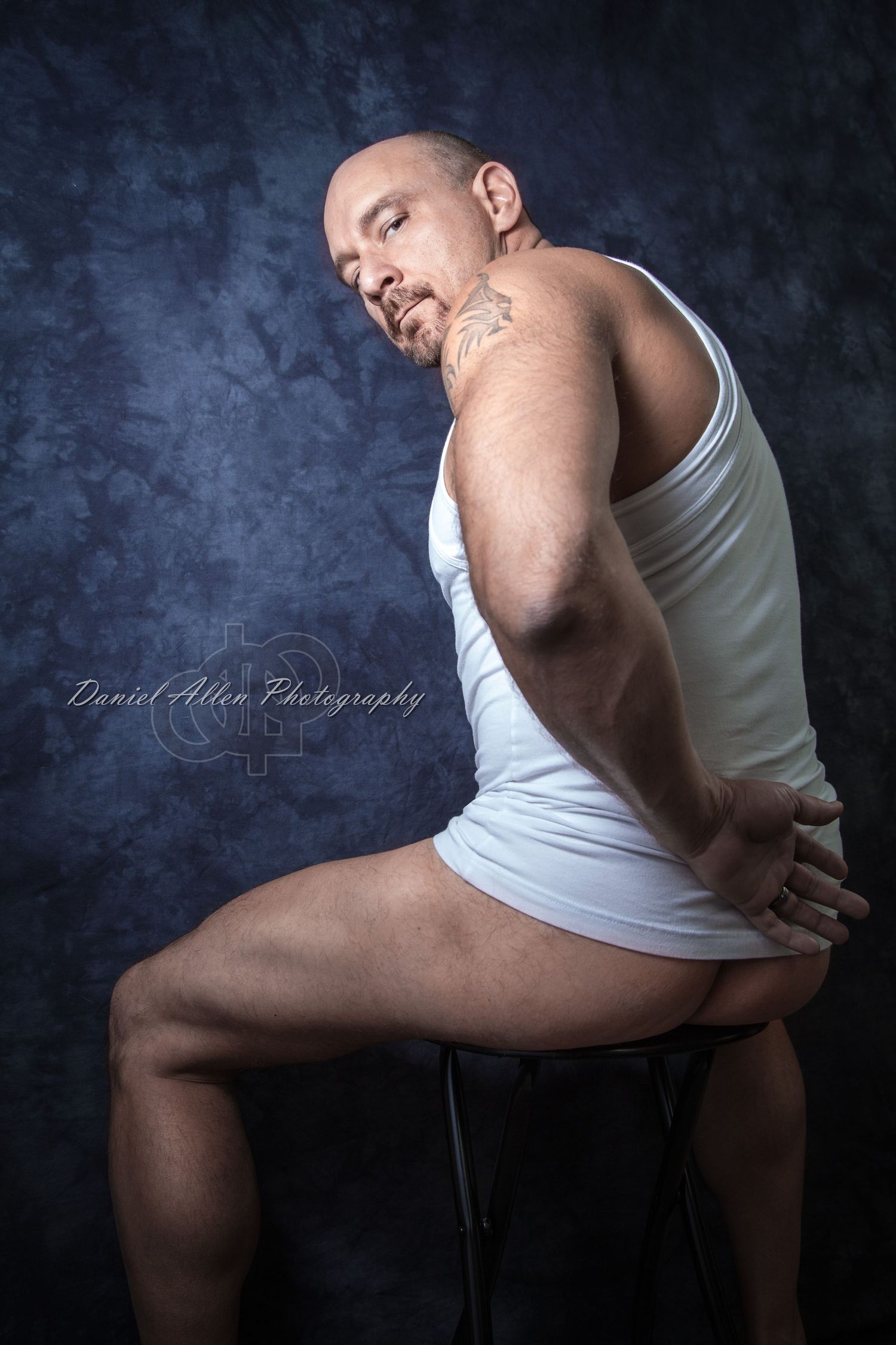 Artistic portrait showcasing athletic form in white tank top against moody backdrop.