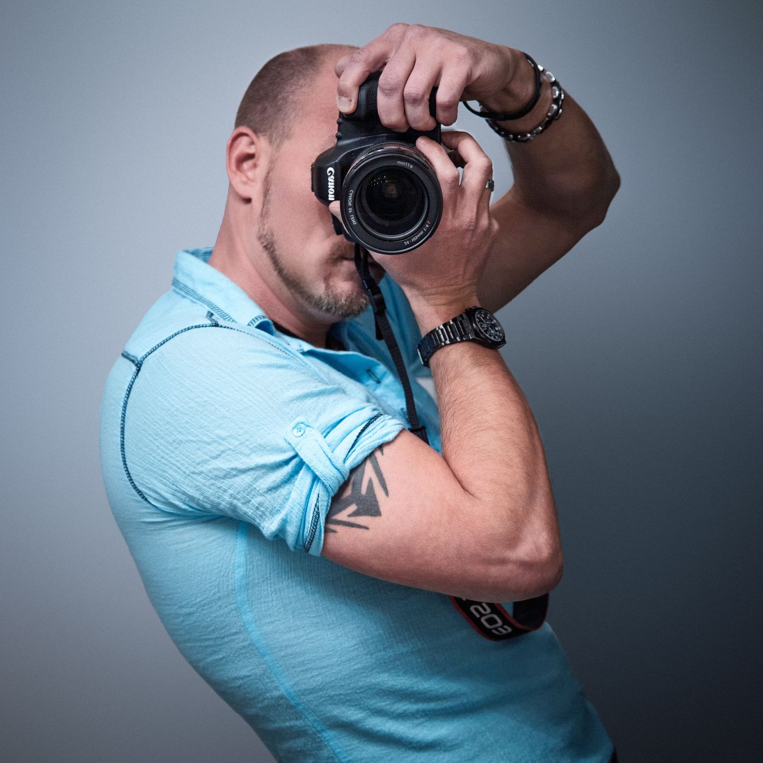 Professional photographer demonstrating camera techniques wearing a light blue polo shirt.