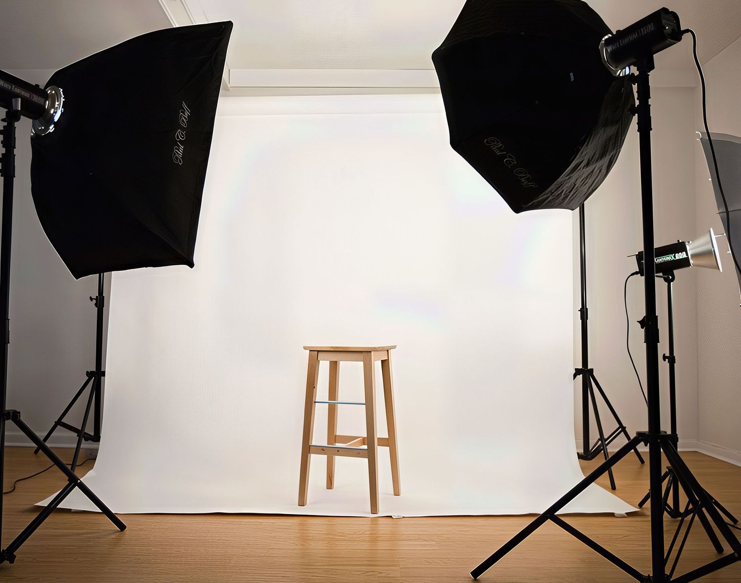 Professional photography studio setup with lights, backdrop and wooden stool.