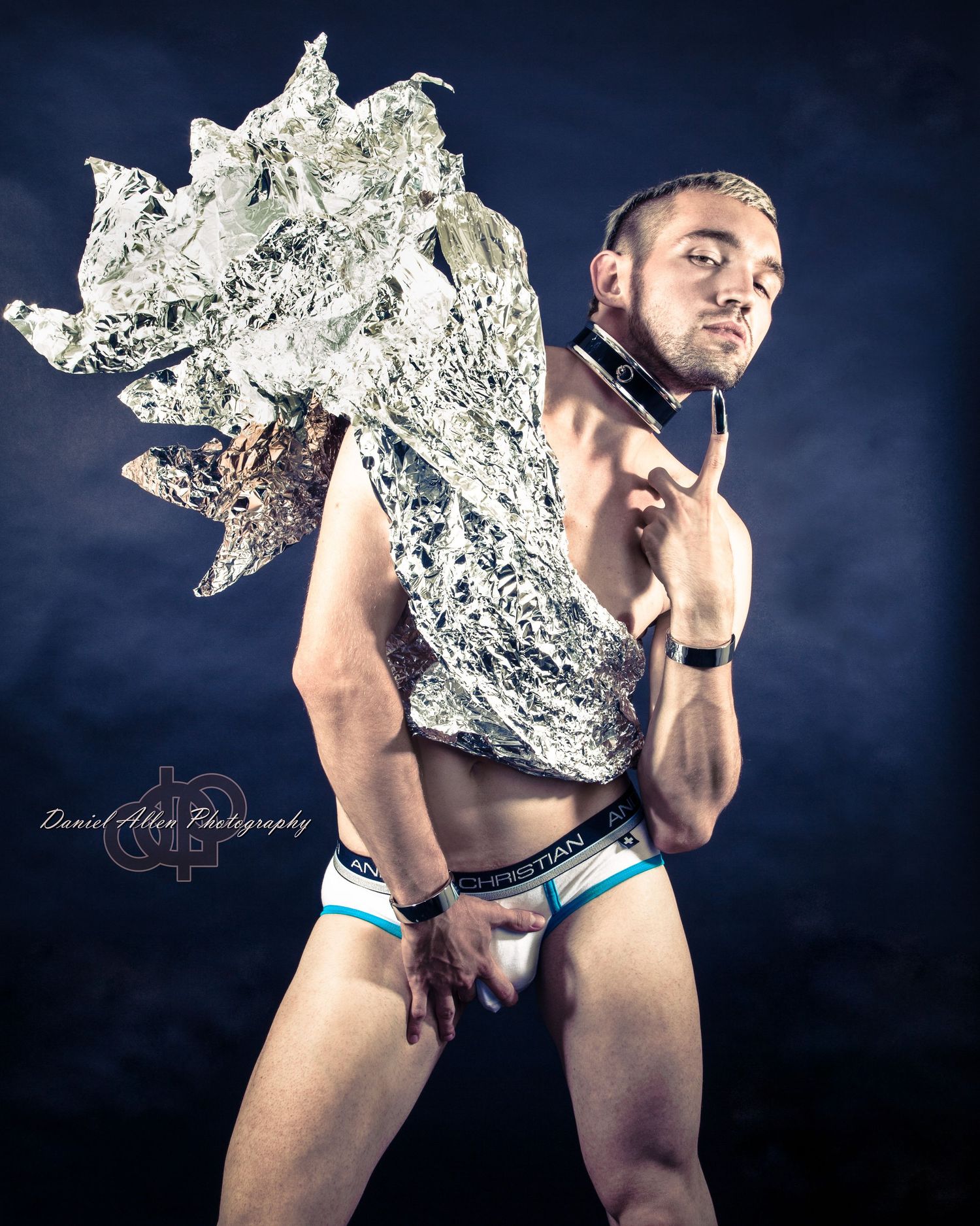 Dramatic studio portraits with flowing silver fabric creating dynamic movement against blue backdrop.
