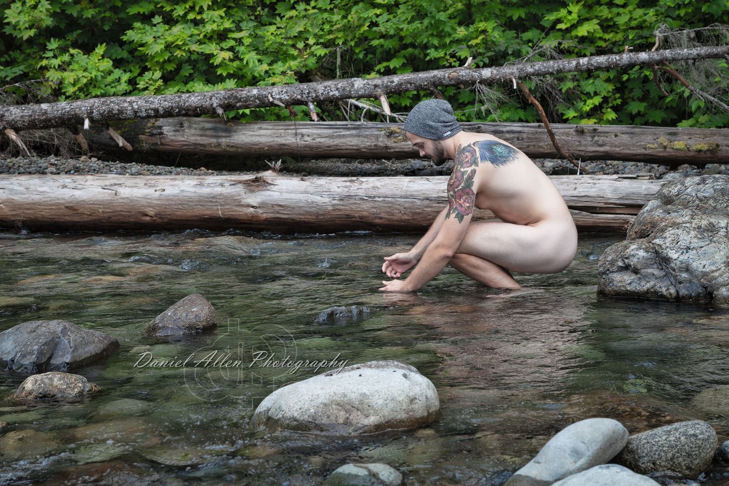 People swim and relax in a crystal clear natural pool surrounded by fallen logs and rocks.
