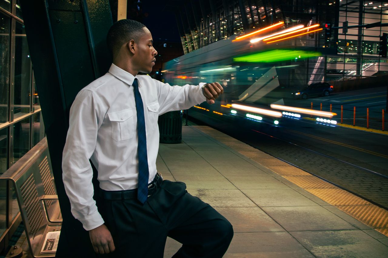 Urban nighttime portrait of businessman in white shirt and tie on train platform.