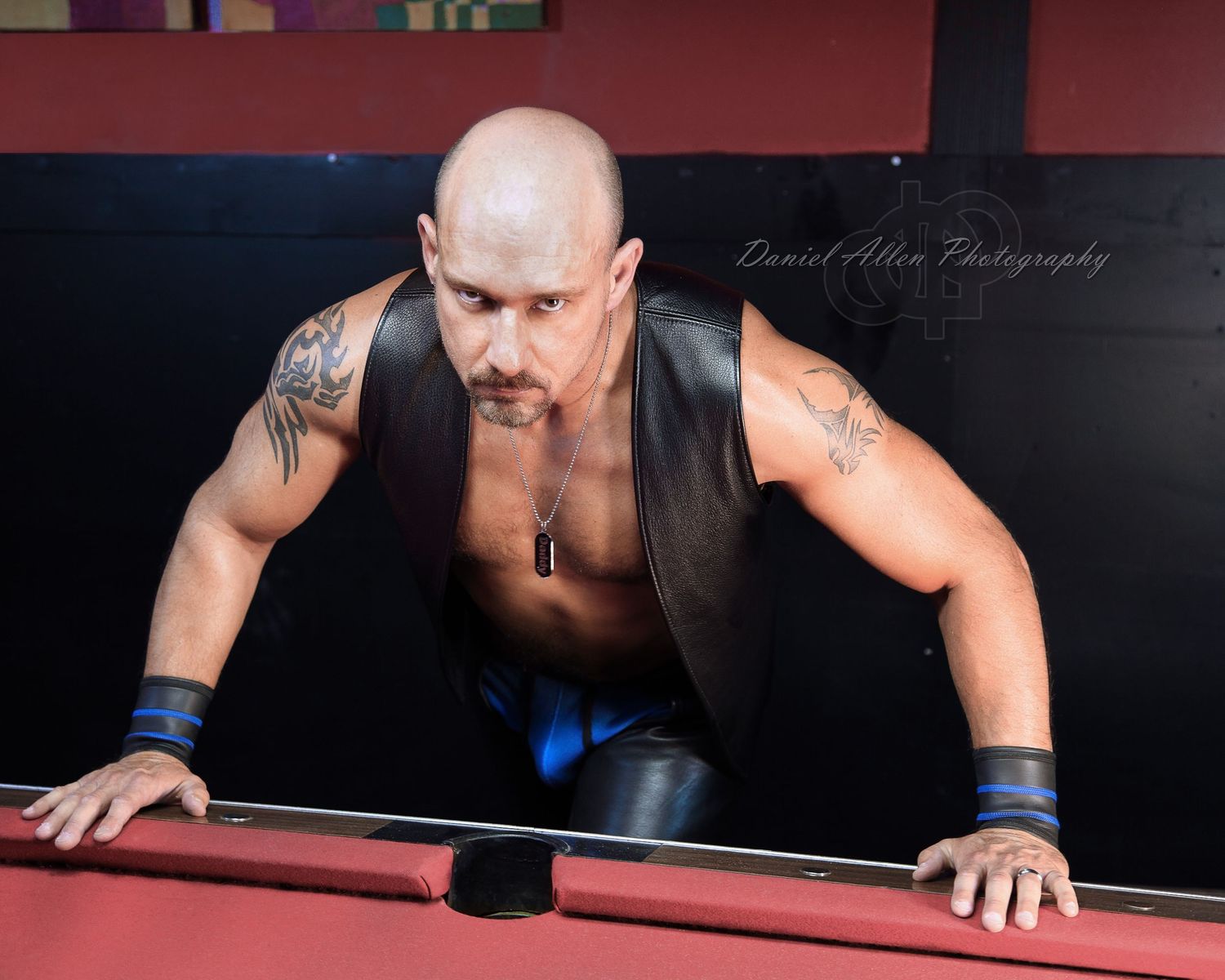 Professional pool player leans over red-felted billiards table preparing to make a precise shot during tournament play.