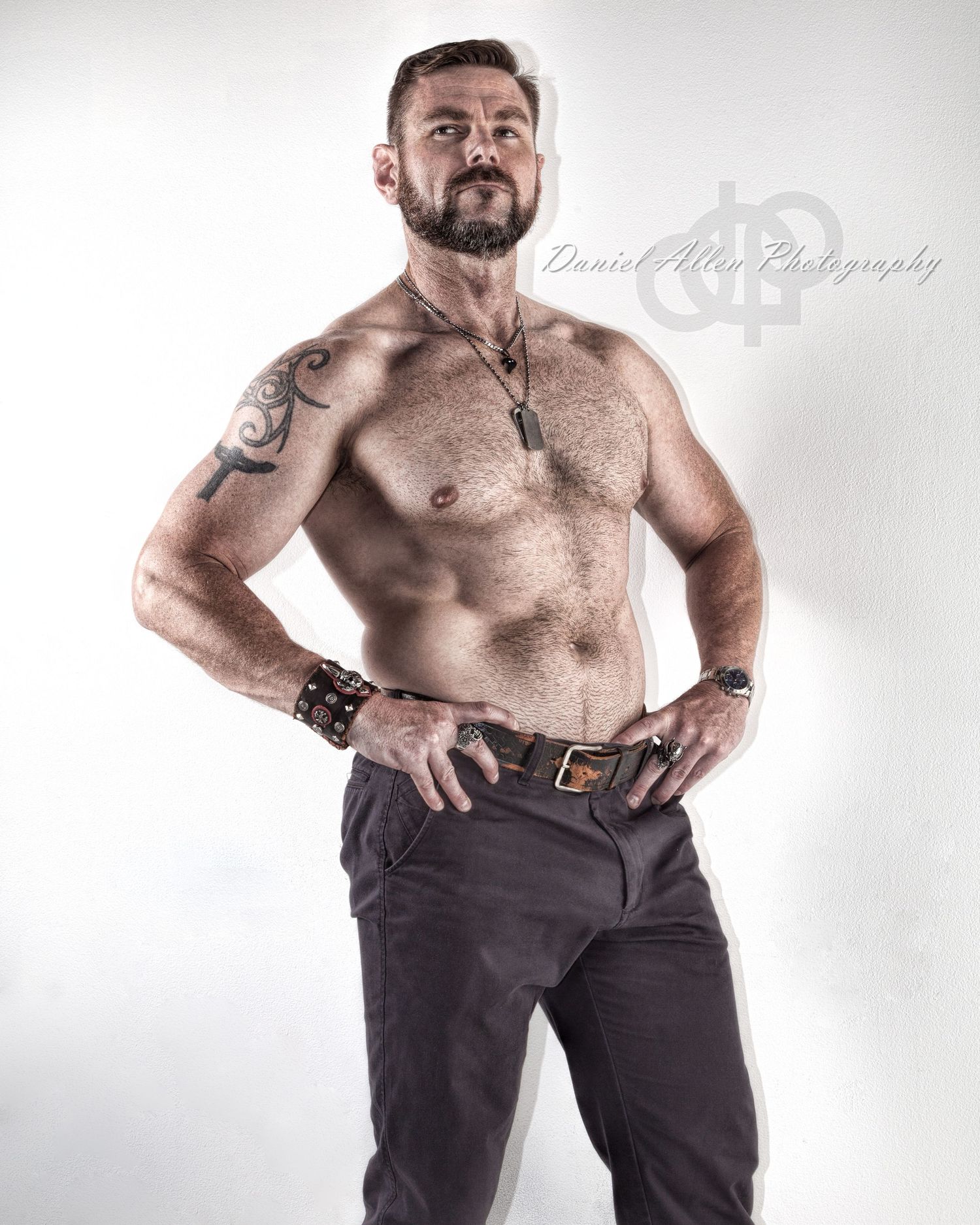 Muscular figure in dark pants poses against white background showing athletic physique.