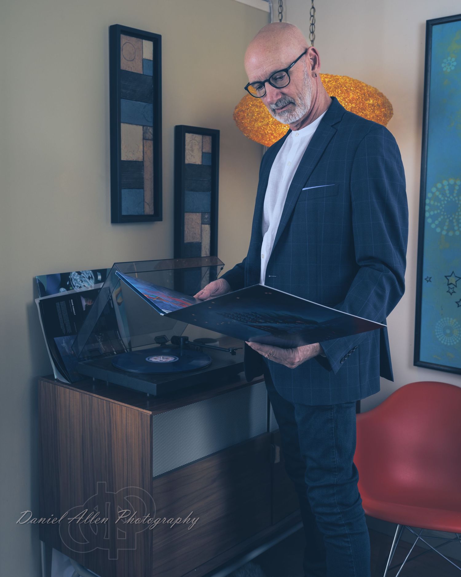 Professional in a dark suit works at a standing desk setup with laptop and multiple monitors in an office space.