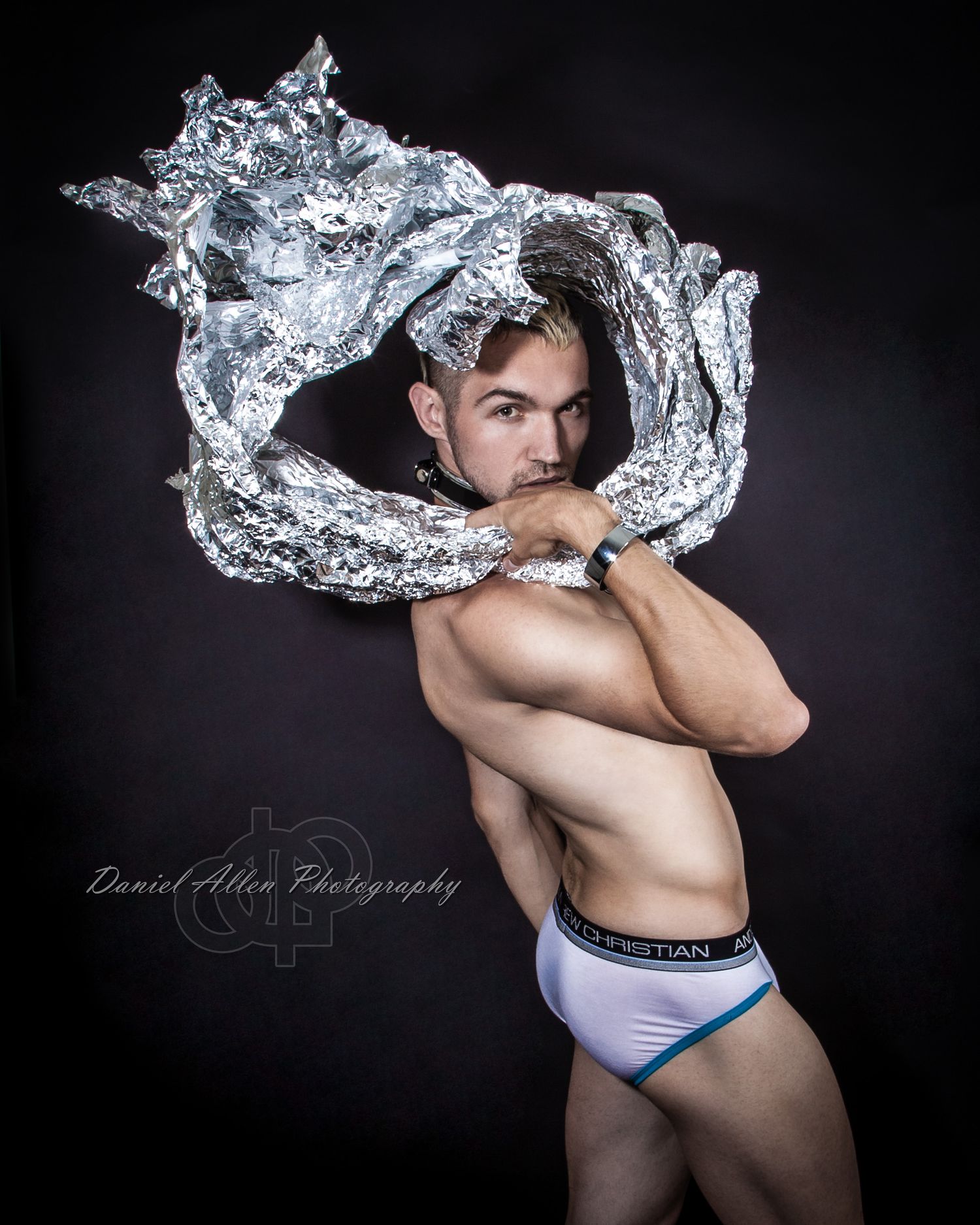 Athletic figure posing with metallic silver fabric in artistic studio photography sequence.