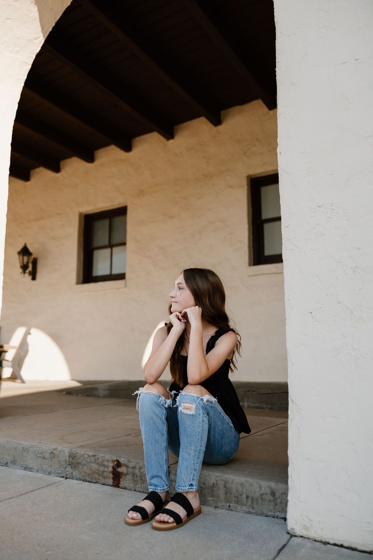 Portrait session in a rustic covered walkway with white walls and wooden beams.