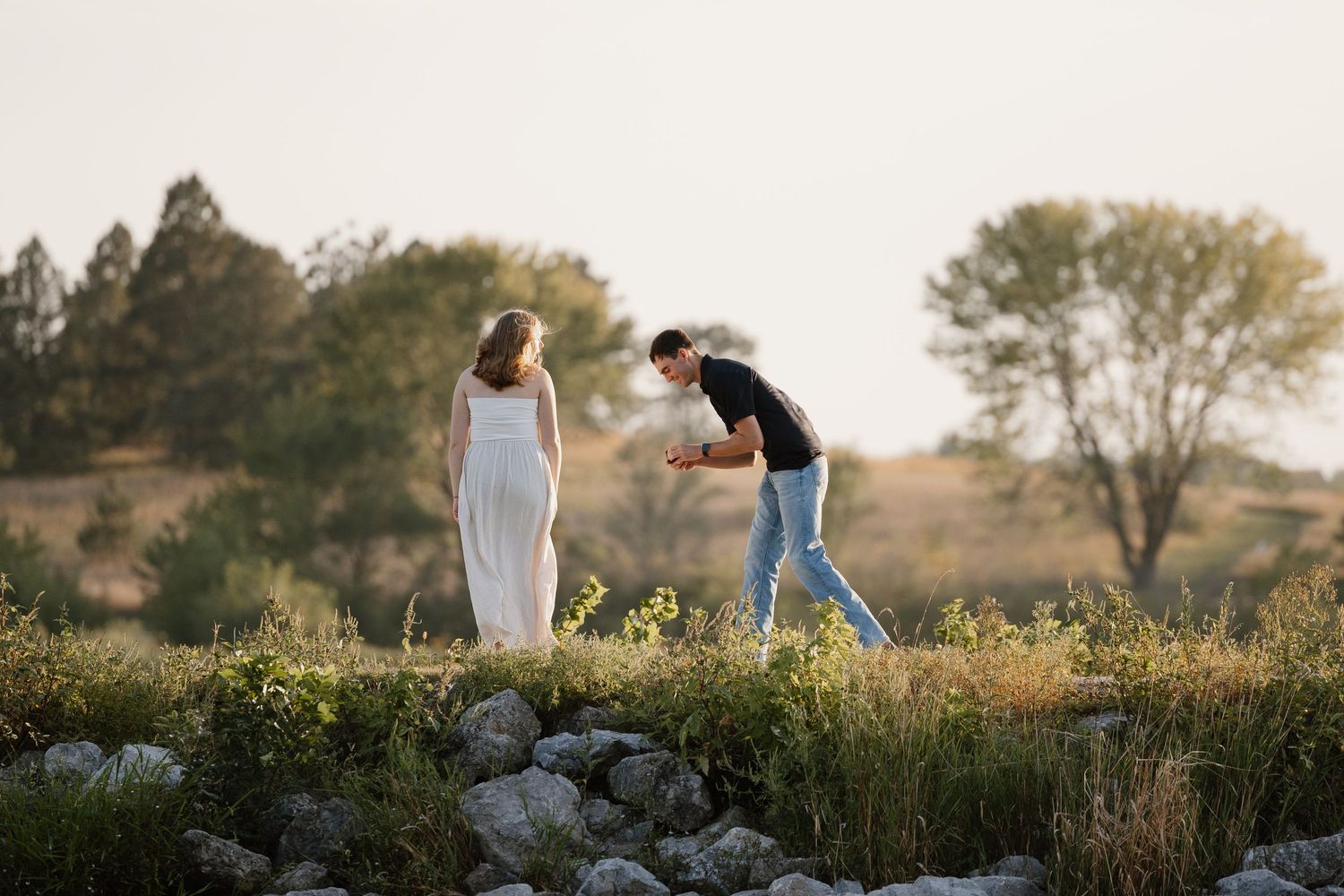 Silhouettes of a couple walking through a scenic field at sunset.