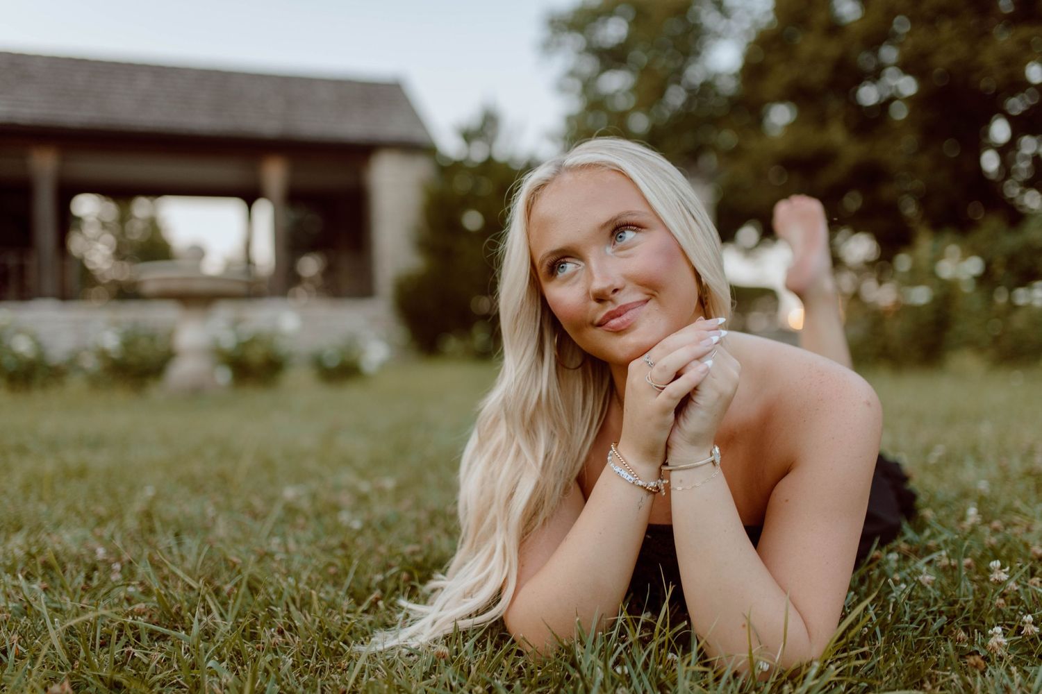 A summer outdoor portrait lying in grass with a building in the background.