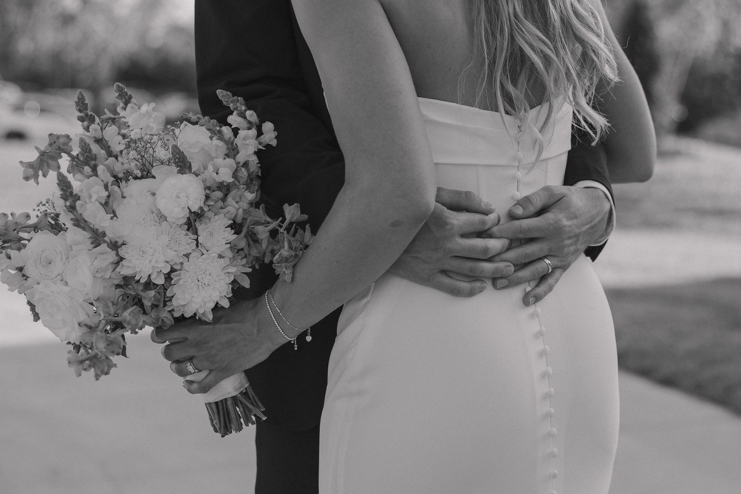 Black and white close-up of bride and groom embracing with bouquet.