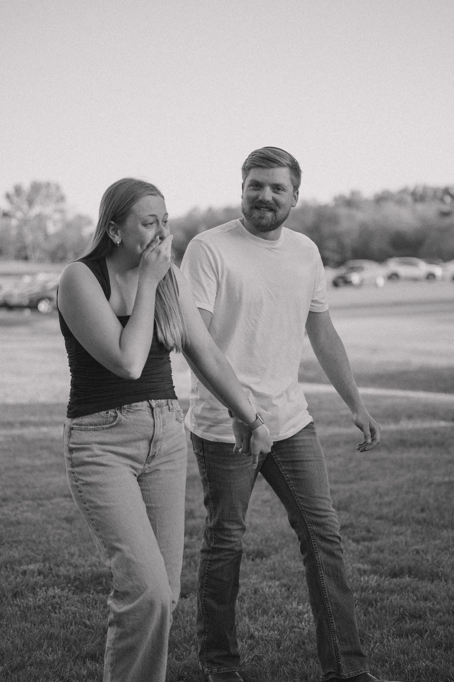 Couple sharing playful moments together on a grassy field.