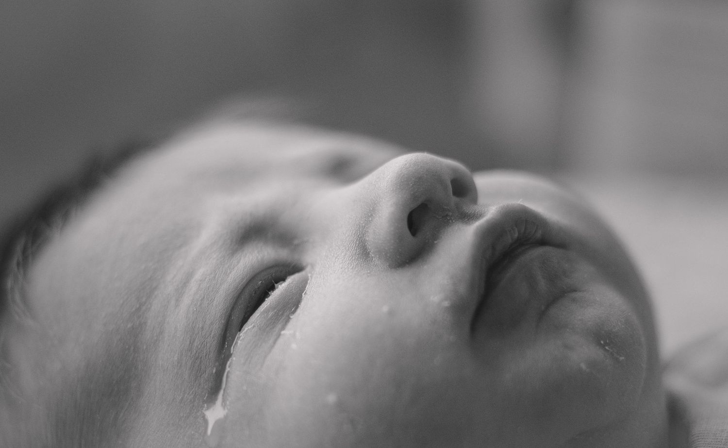 Black and white close-up of a sleeping infant's nose and mouth against a light background.