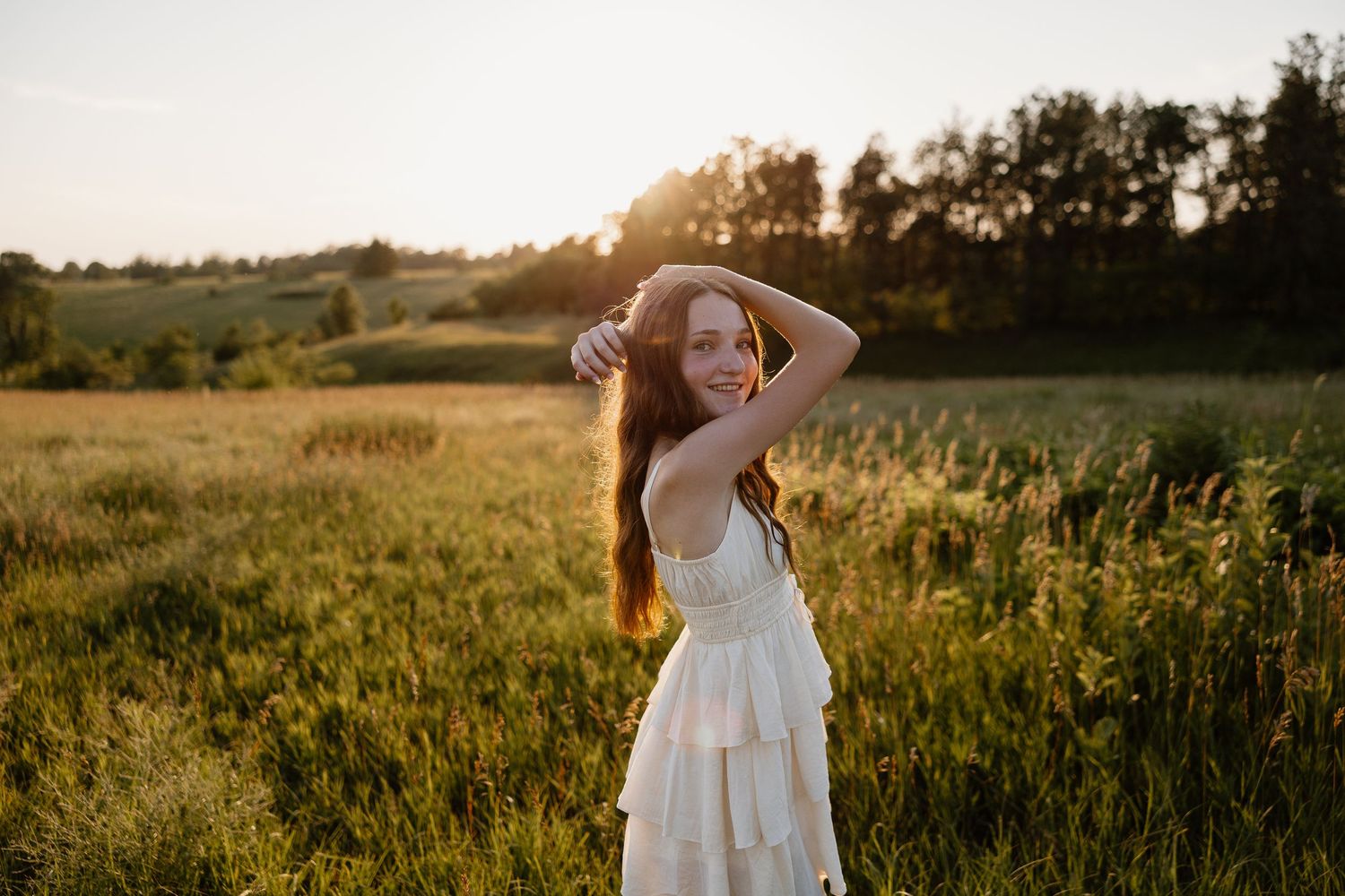 Golden hour portrait session in a sunlit field with tall grass.