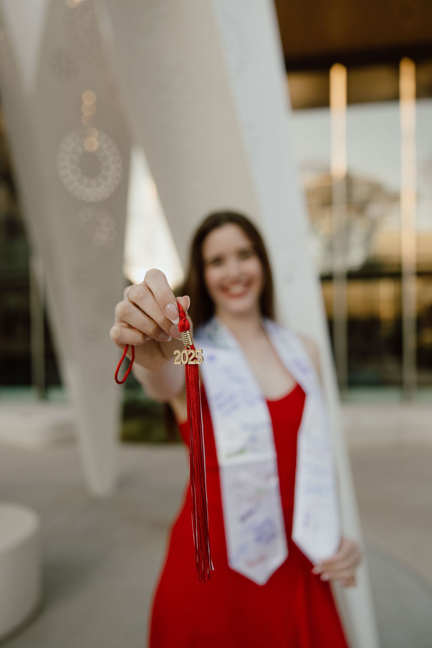 Graduate holding red tassel during outdoor graduation photo session.