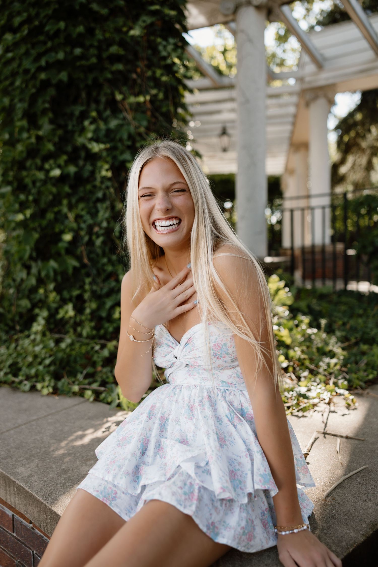 Casual outdoor photoshoot featuring a floral summer dress and natural lighting in a garden setting.
