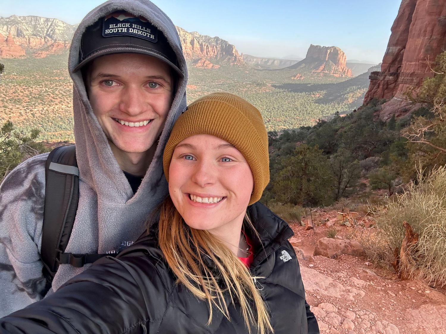 Hiking selfies taken against stunning red rock formations in a desert landscape.