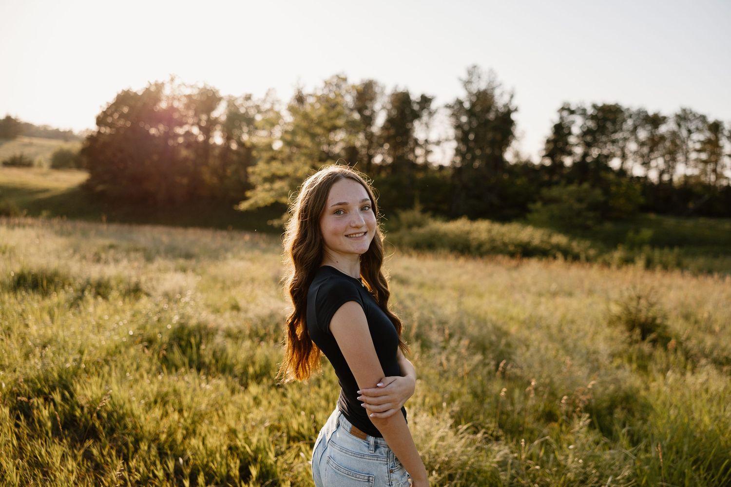 Golden hour portrait session in a grassy field with sunset lighting.