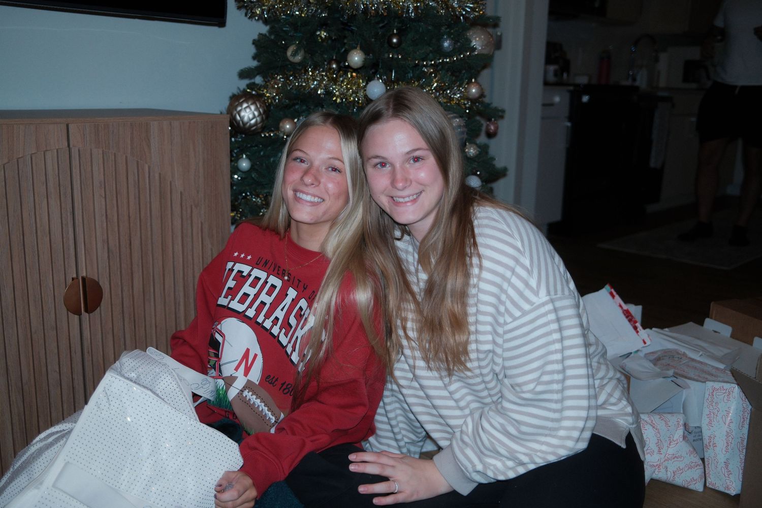 Two people wearing red and white clothing sit together on a couch during a casual gathering.