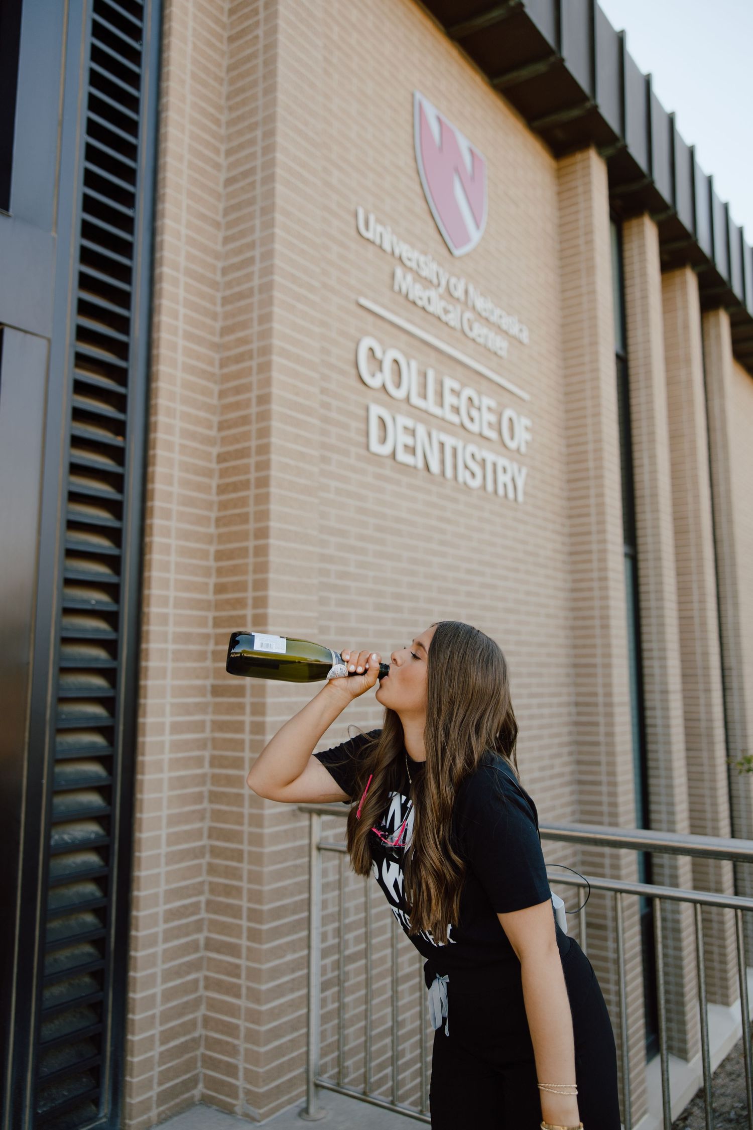 A graduate celebrates with champagne outside the College of Dentistry.