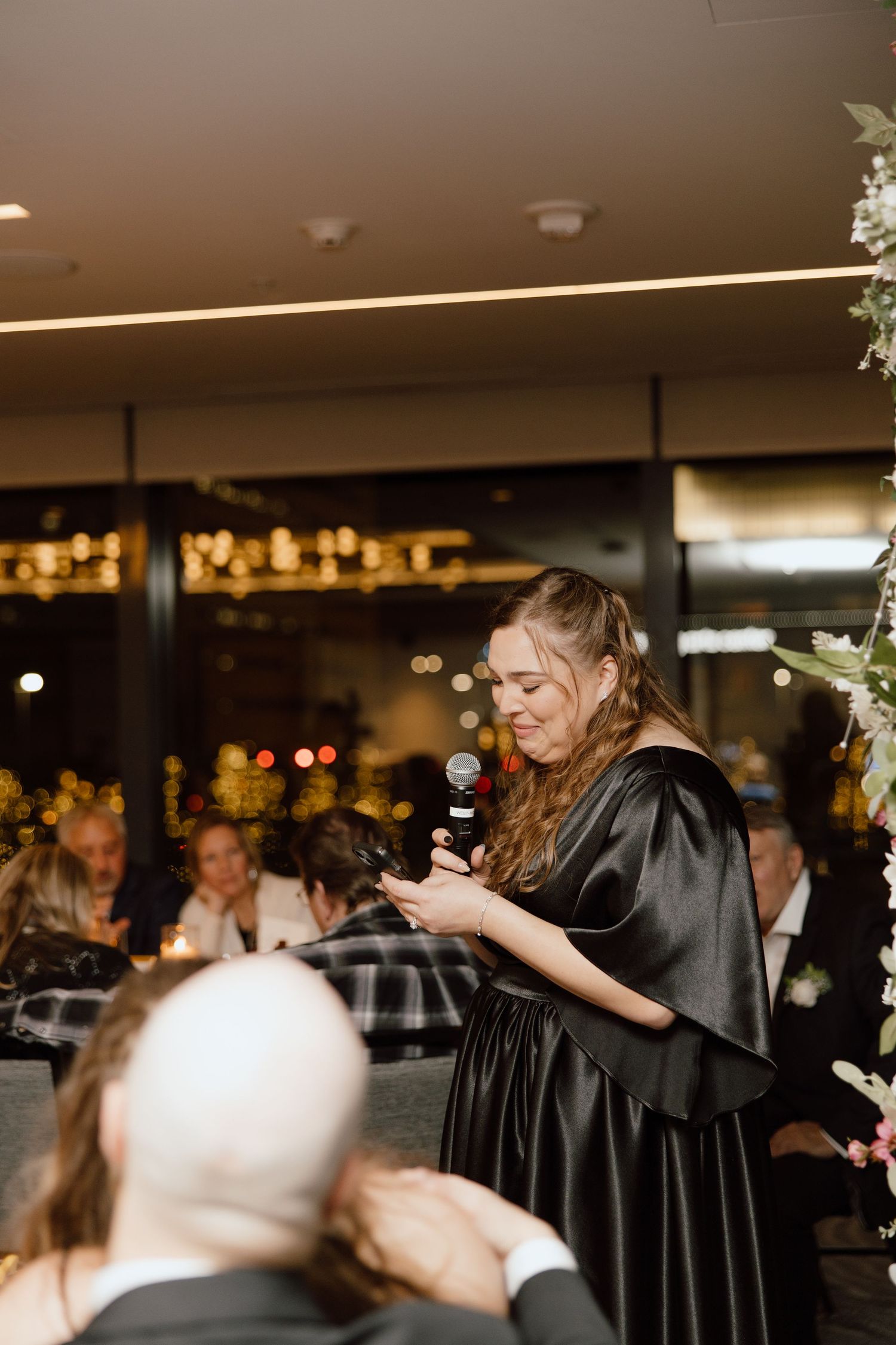 Guest delivers emotional speech at elegant evening wedding reception with floral decorations.