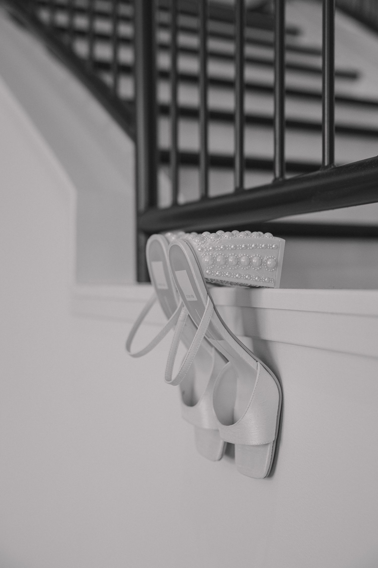 A series of minimalist black and white photographs showing a white plastic hand clip attached to a shelf or ledge.