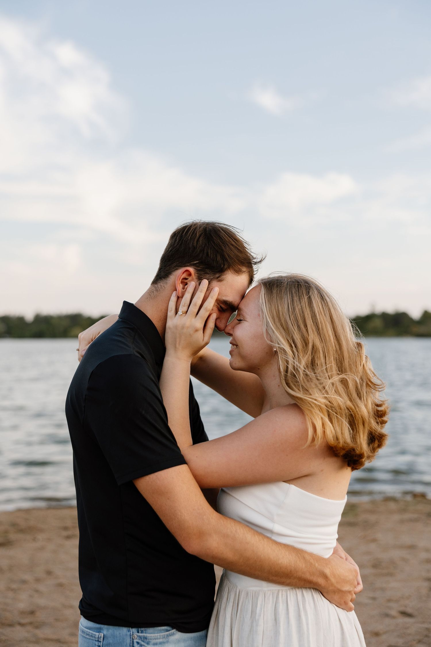 Romantic beach engagement photos with couple embracing by the water.