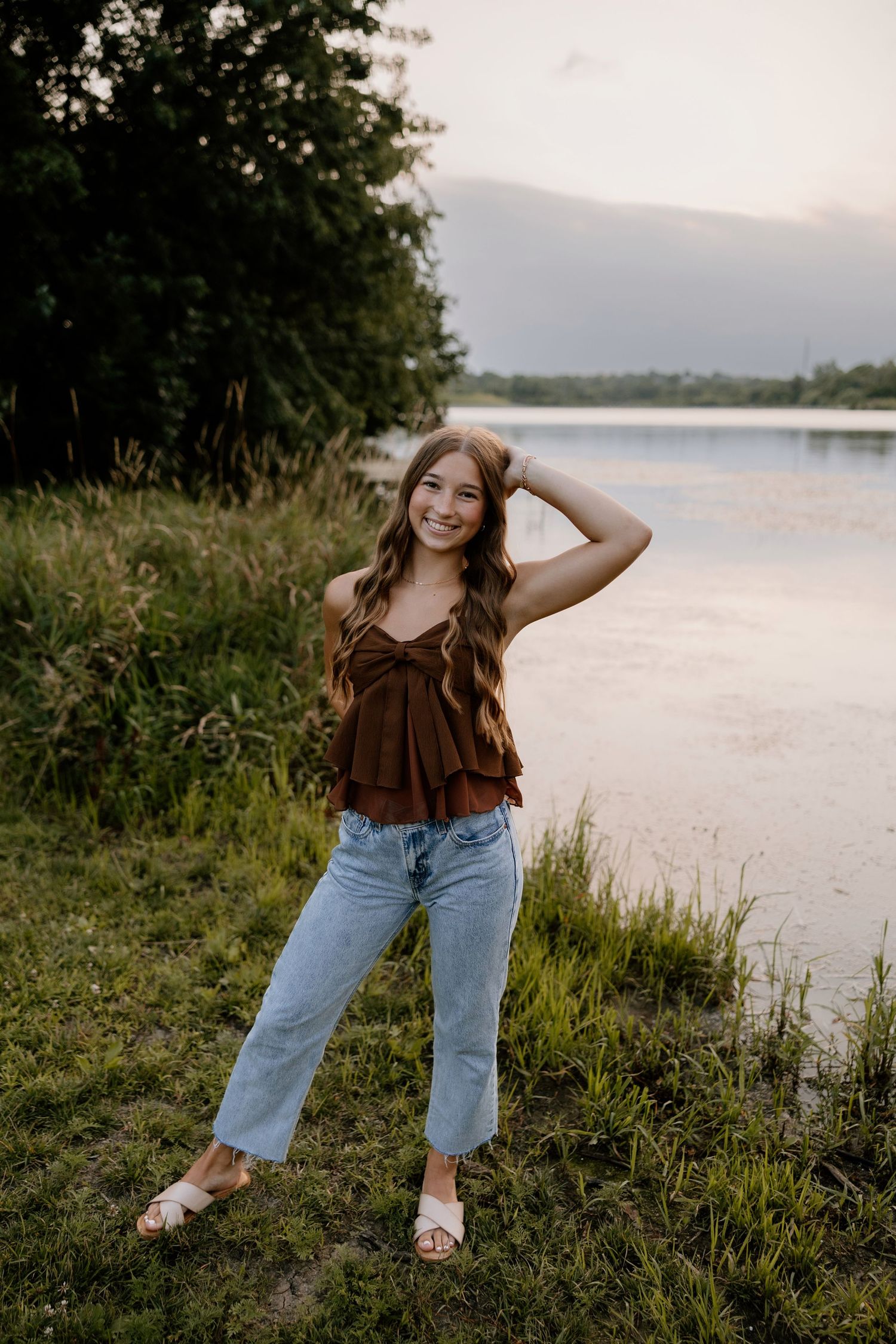 Casual portrait session by a lake at sunset with natural foliage in the background.