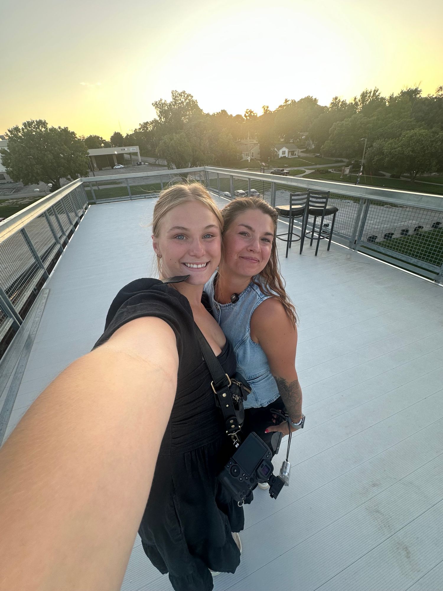 A rooftop selfie of two photographers at sunset with camera gear.