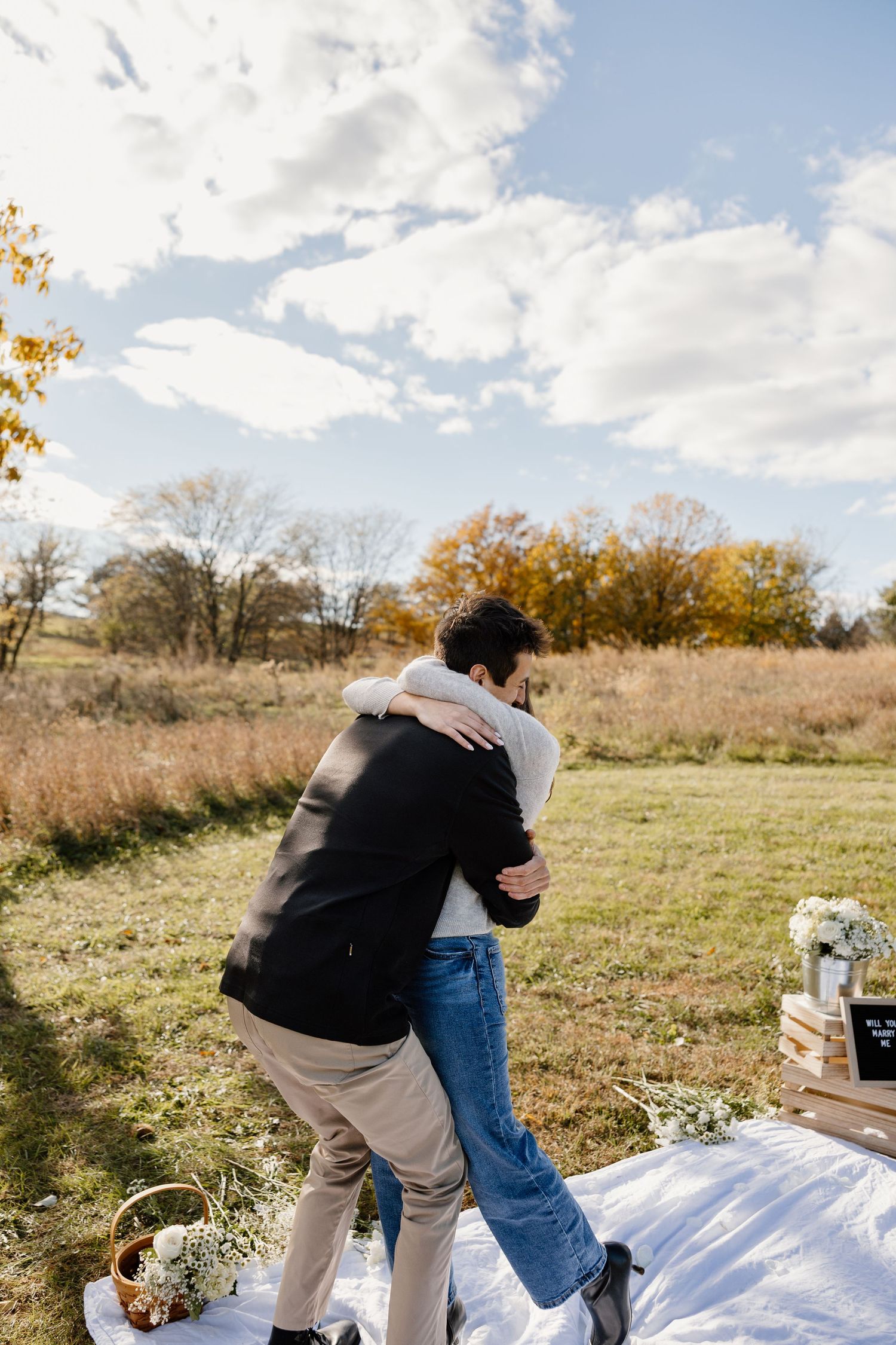 Joyful celebration moments after a proposal in an autumn field setting.