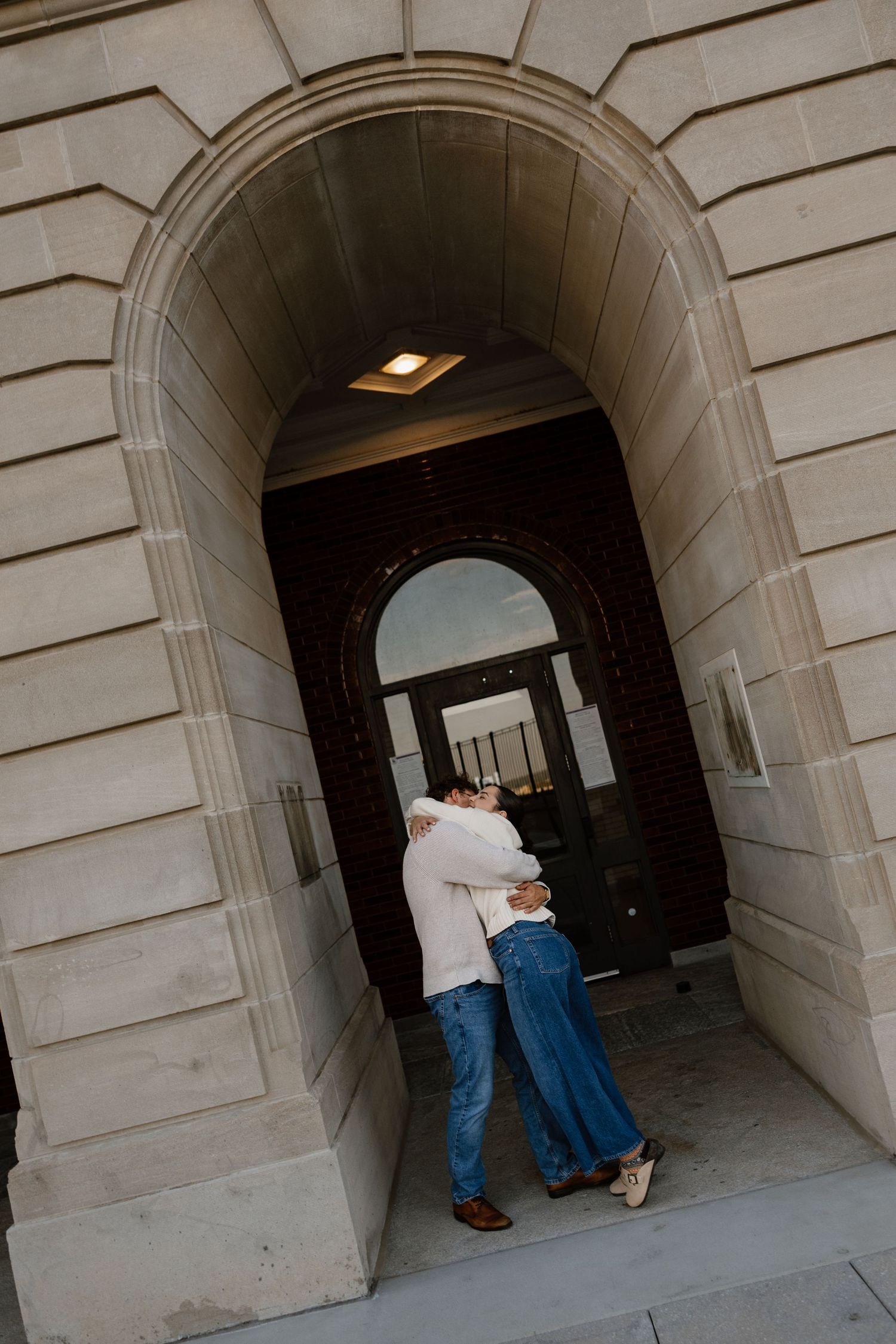 Romantic couple embracing in stone archway of historic building.