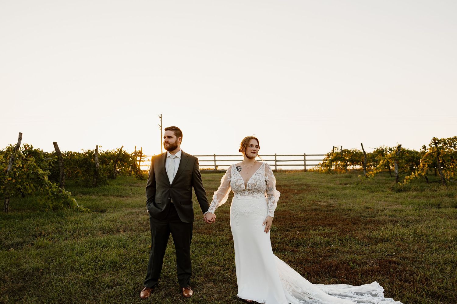 Couple walking through grassy field during golden hour wedding photoshoot.