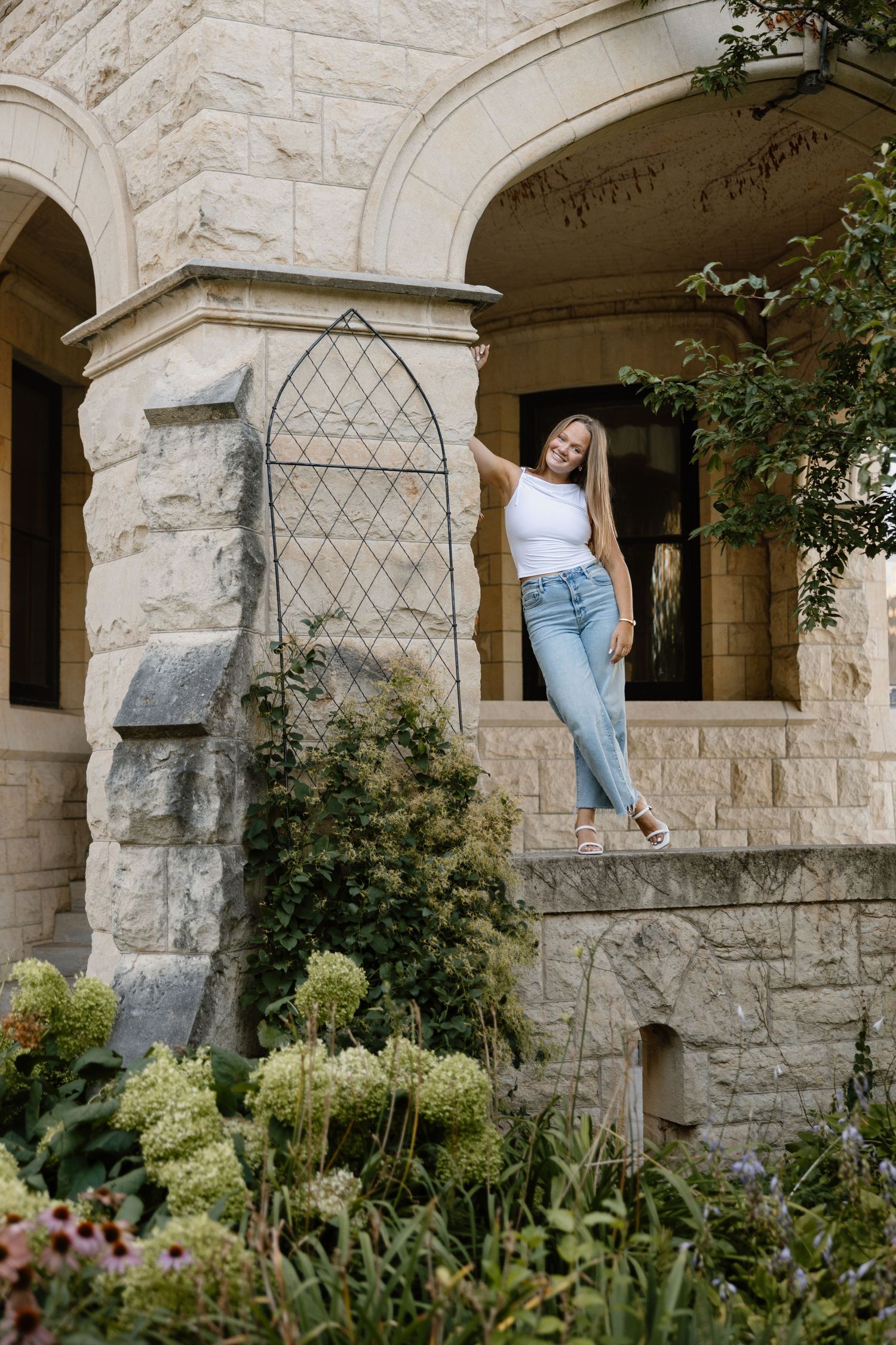 Stone building exterior with arched columns and garden landscaping.
