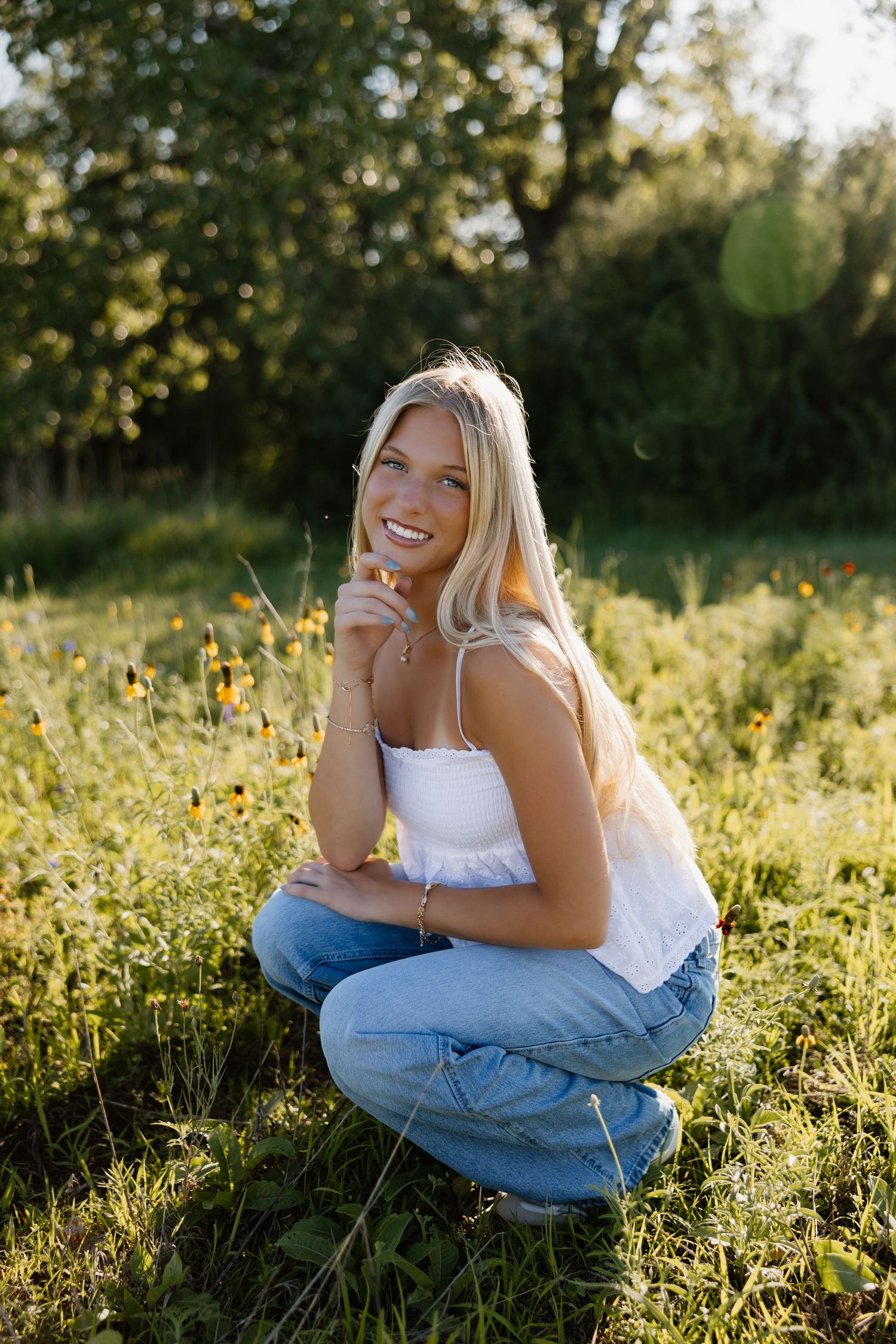 Summer sunset photoshoot in a wildflower field wearing casual denim and white top.